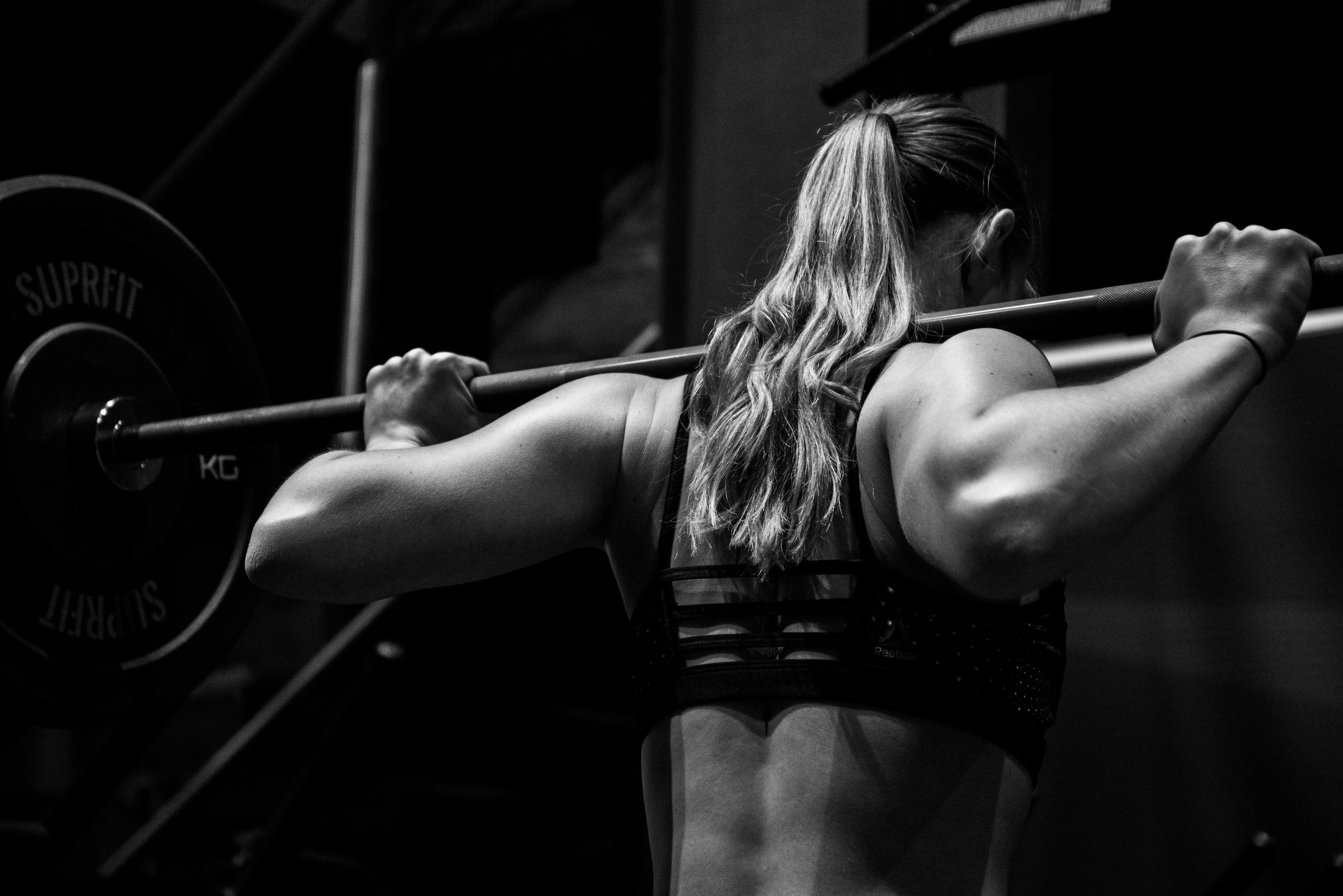 A woman with a barbell on her back about to squat