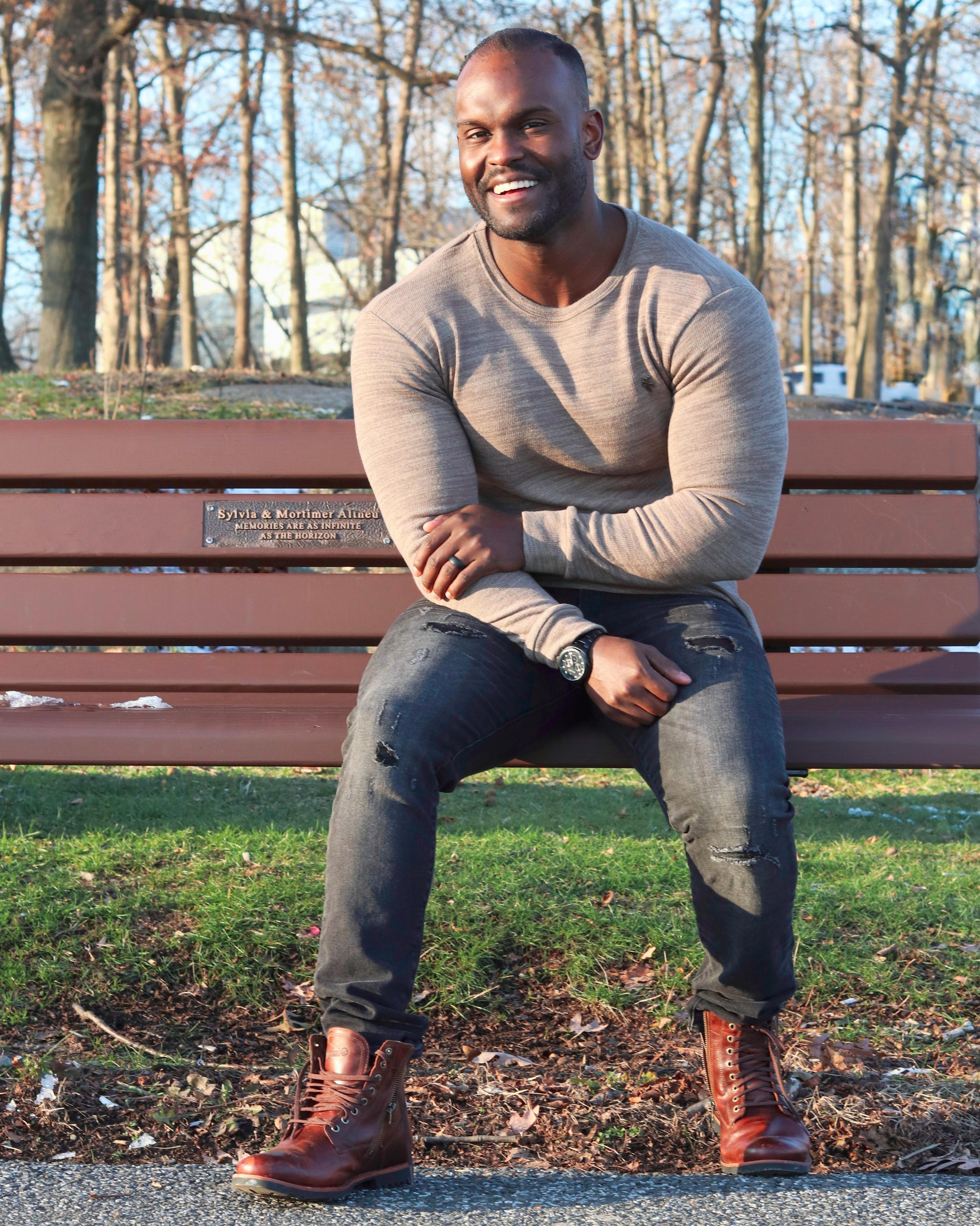 A man sitting on a bench at the park smiling