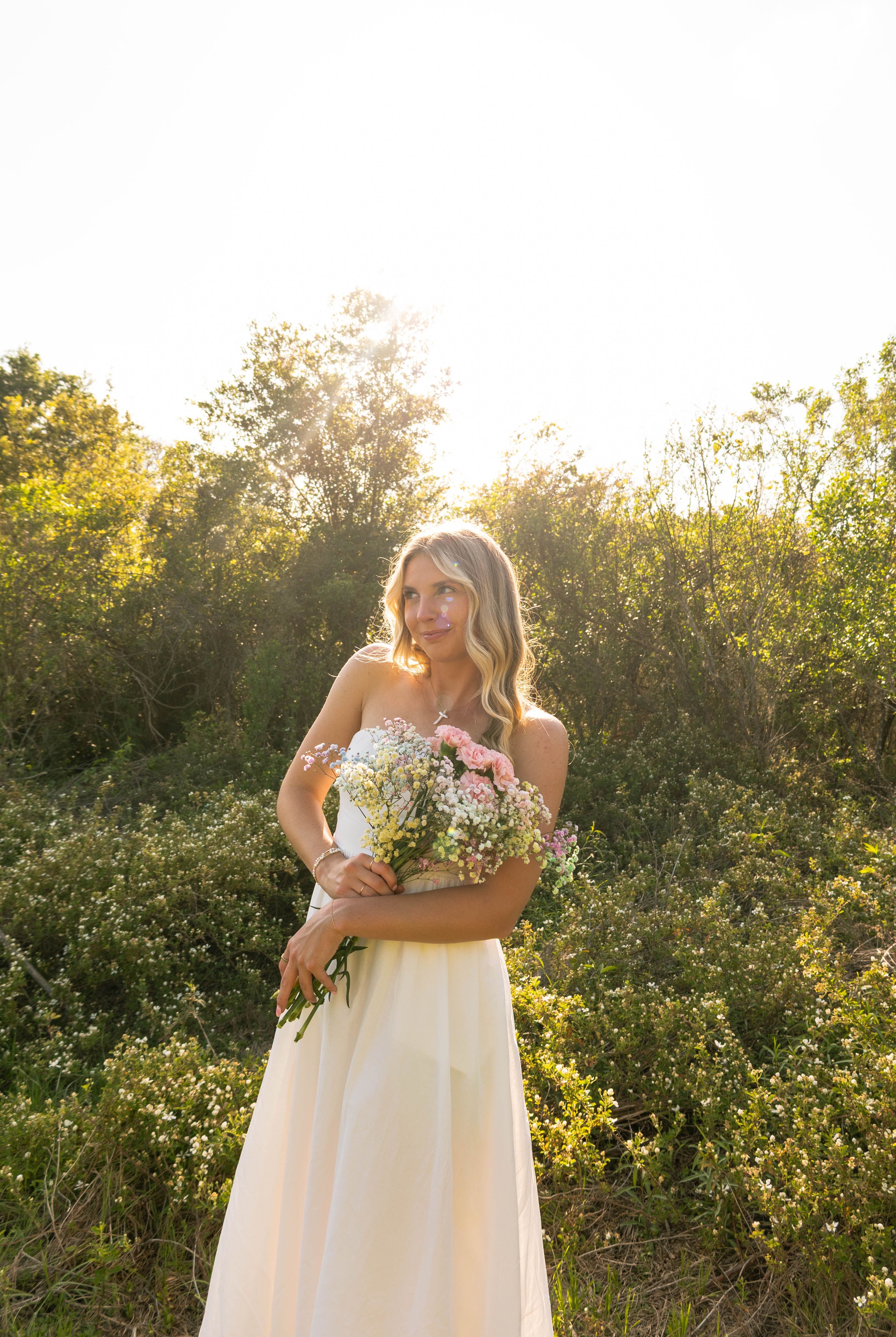 girl in white dress holding bouquet of flowers in garden