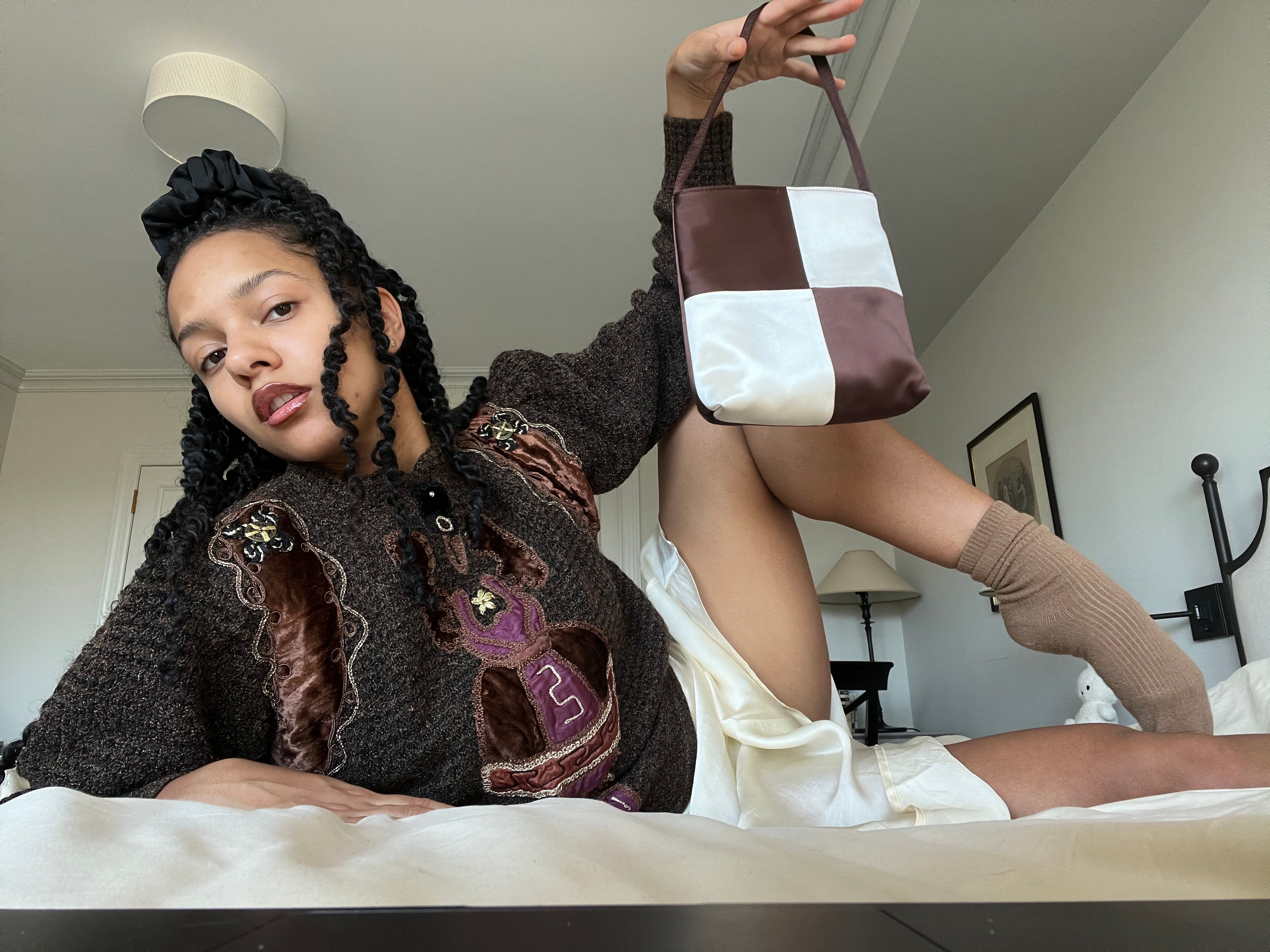 Actor Djouliet Amara poses with a Hai checkerboard silk bag in brown and white