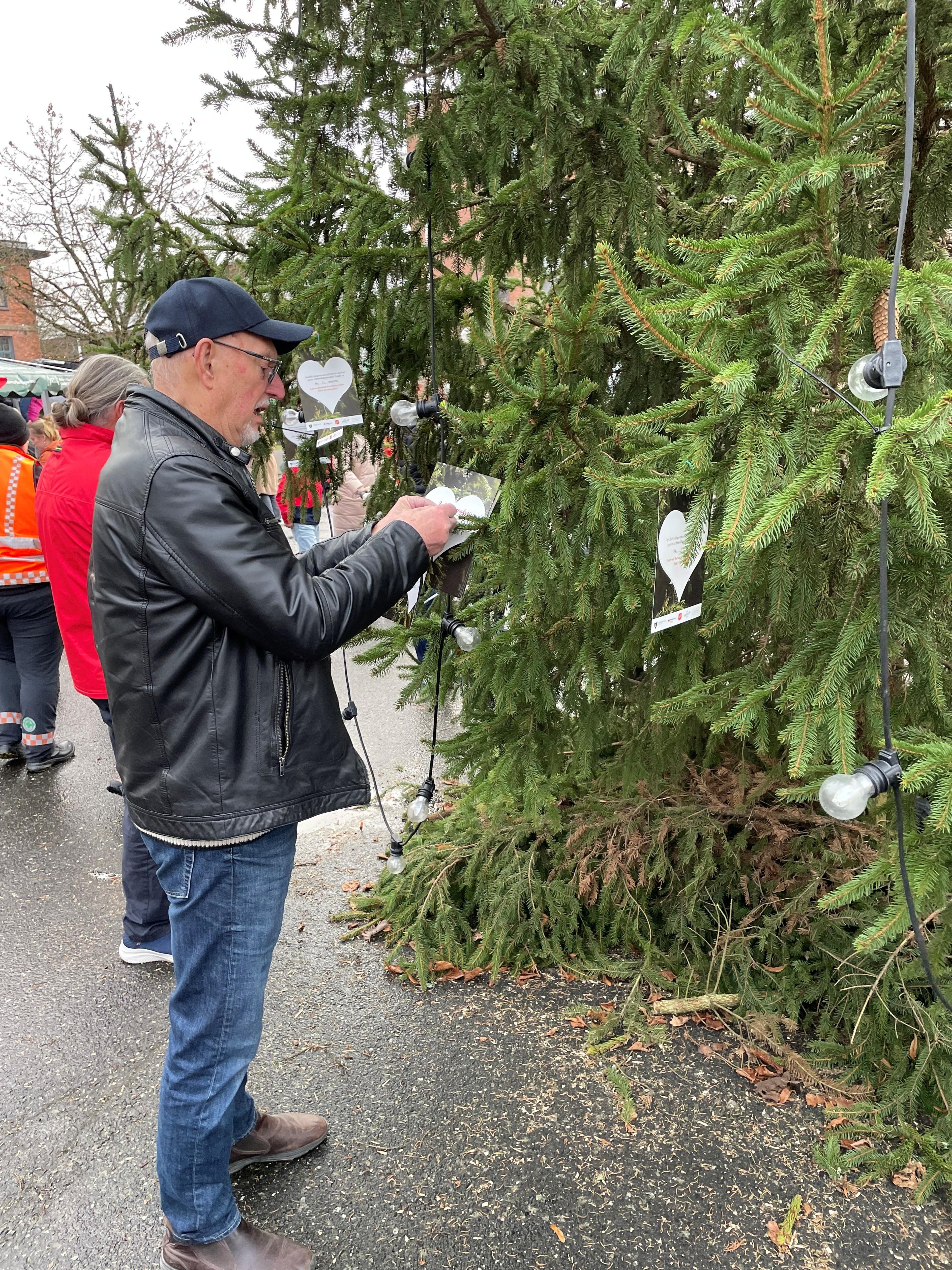 En mann som henger opp kort på et tre.