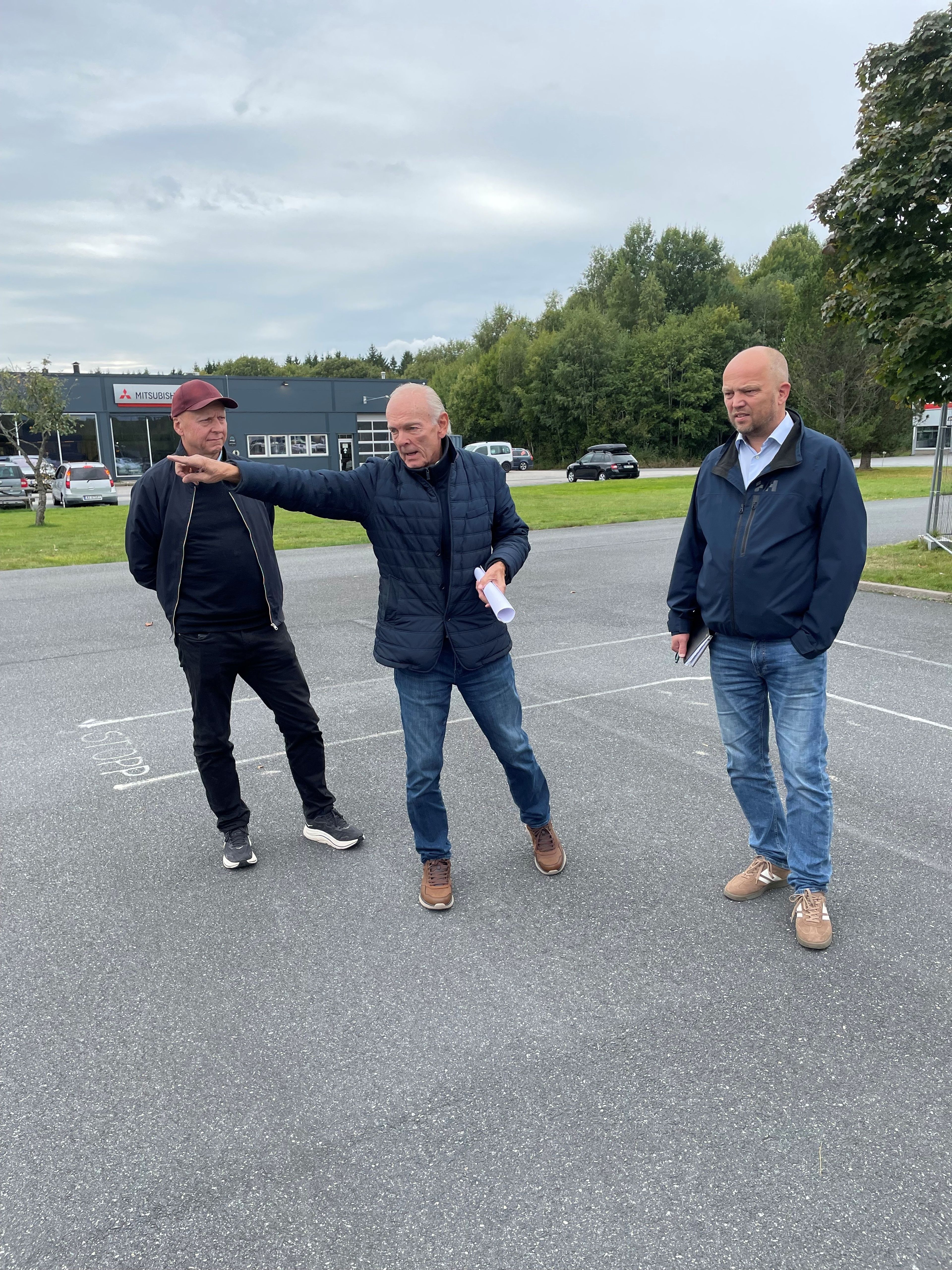 Tre menn på en asfaltplass
