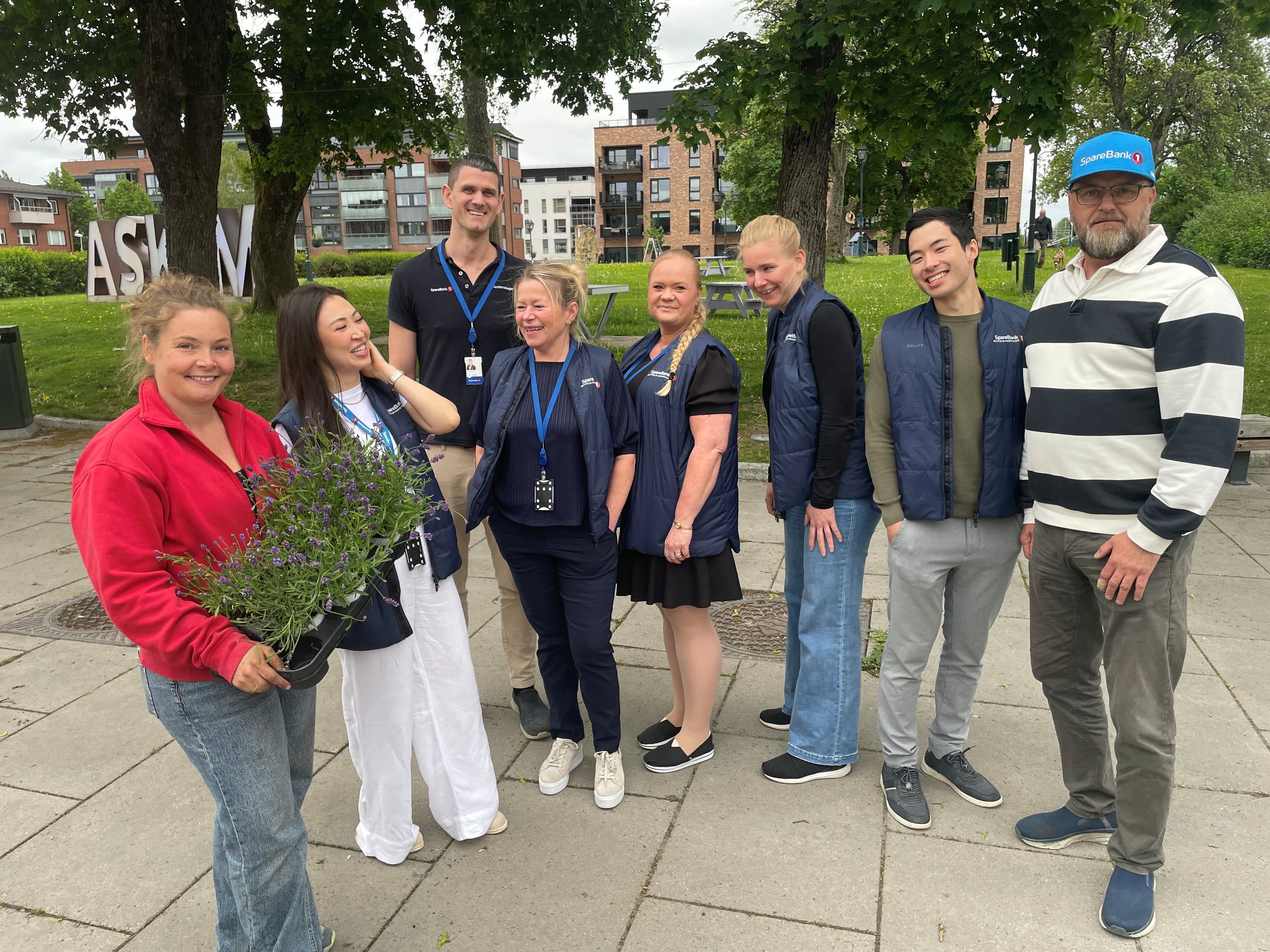 Åtte mennesker foran en park, med masse blomster