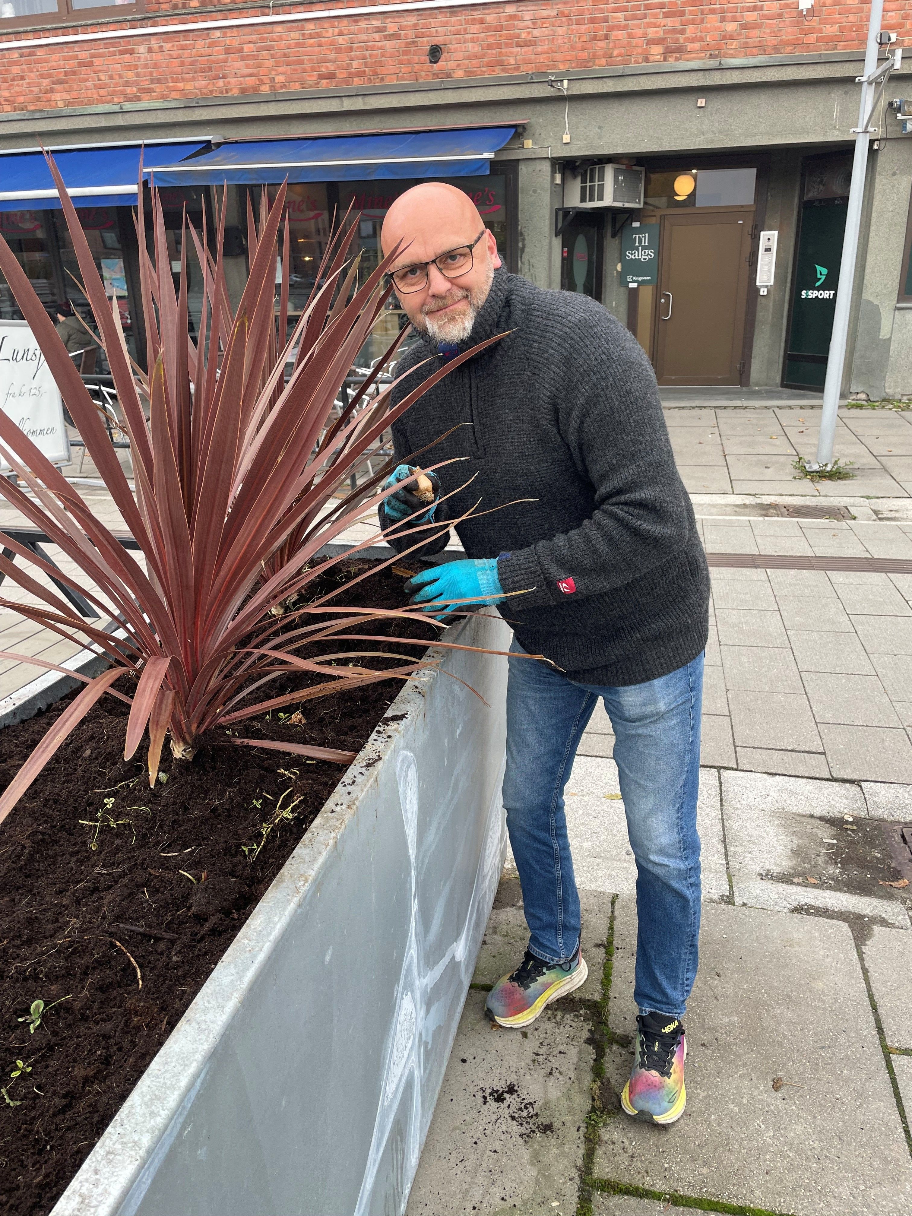 mann som planter løk i gågata