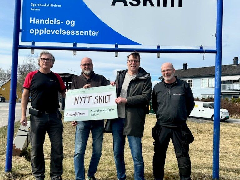 Glade herrer foran velkommen til Askim skiltet