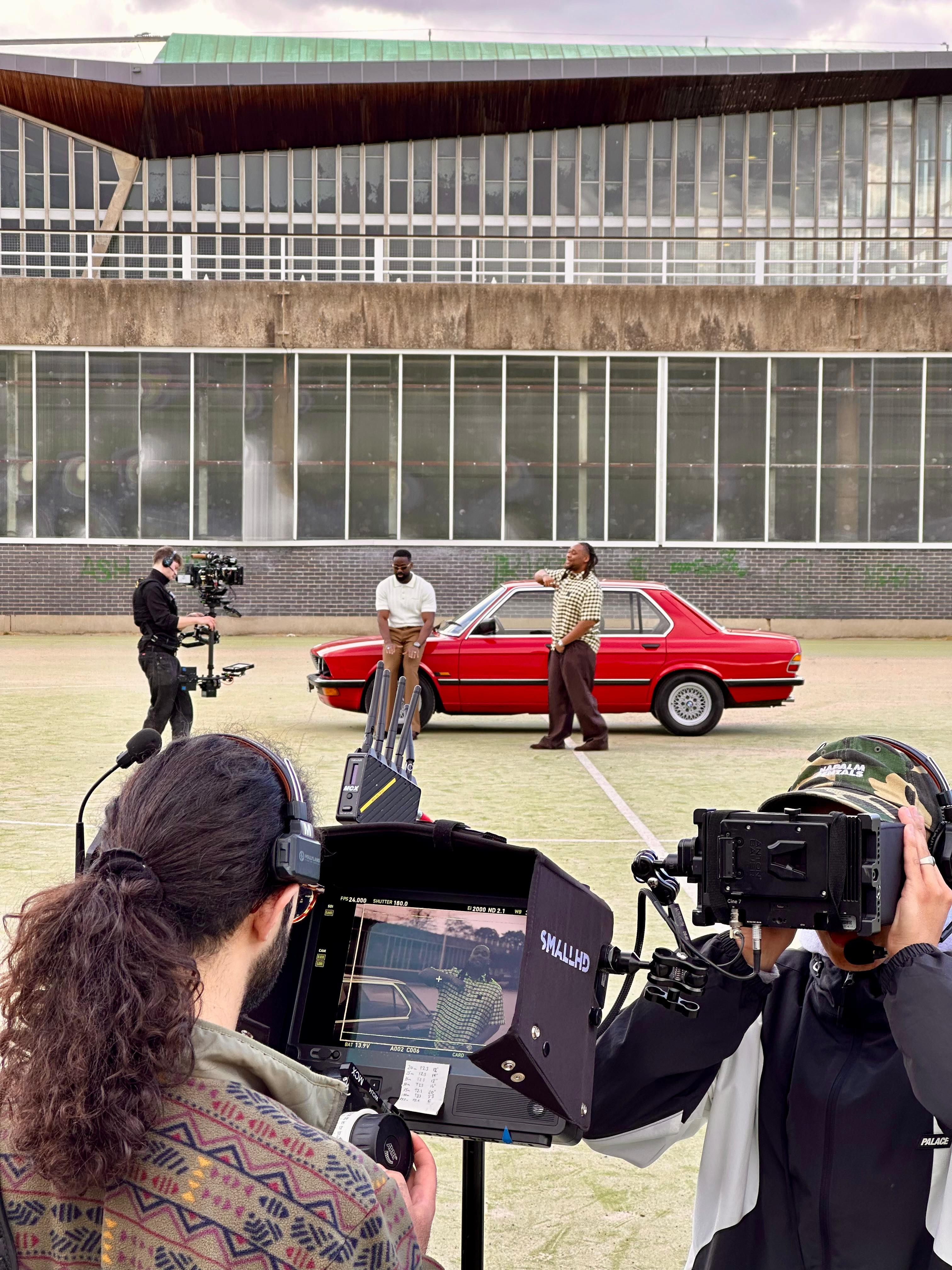 Filming two men in front of red BMW