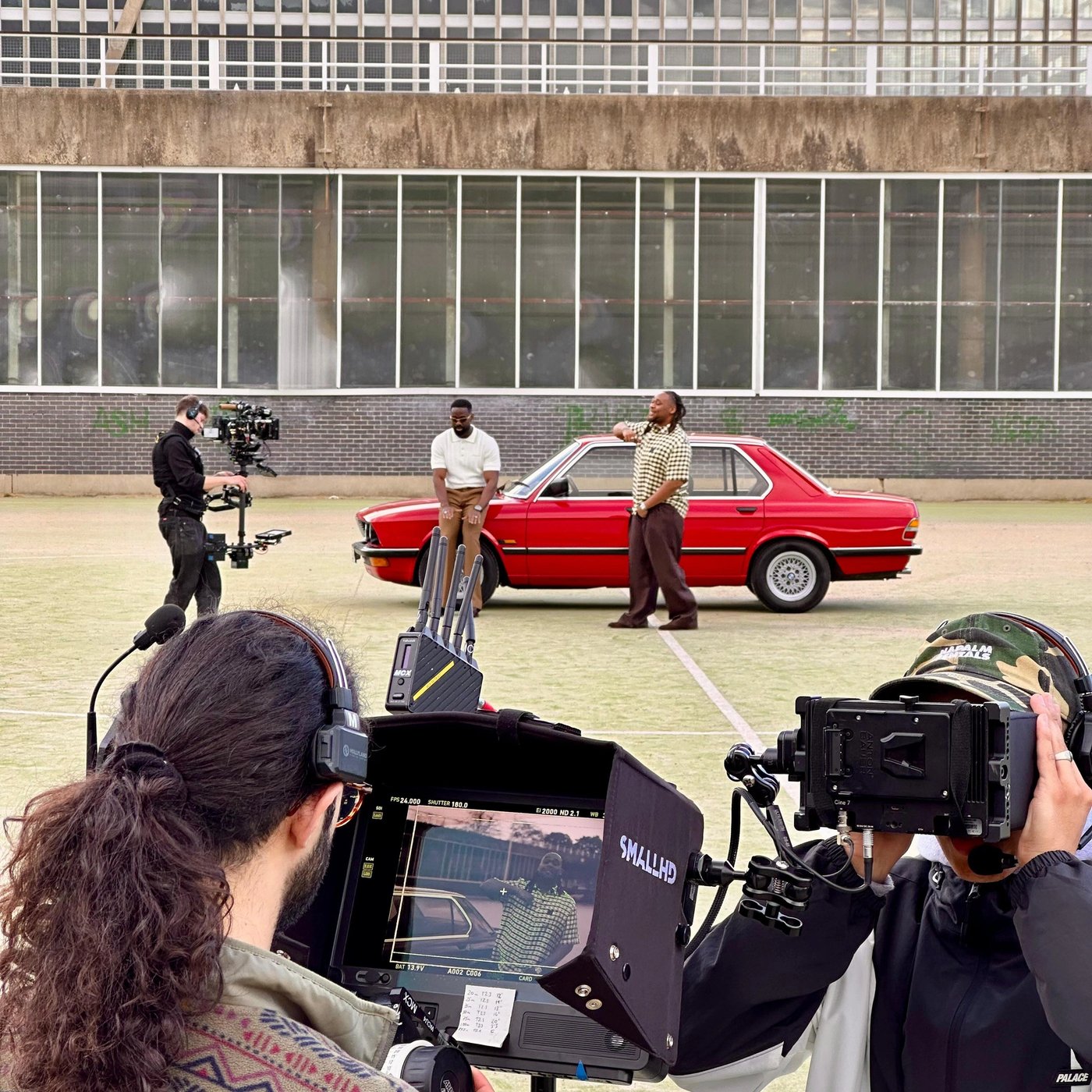 Filming two men in front of red BMW
