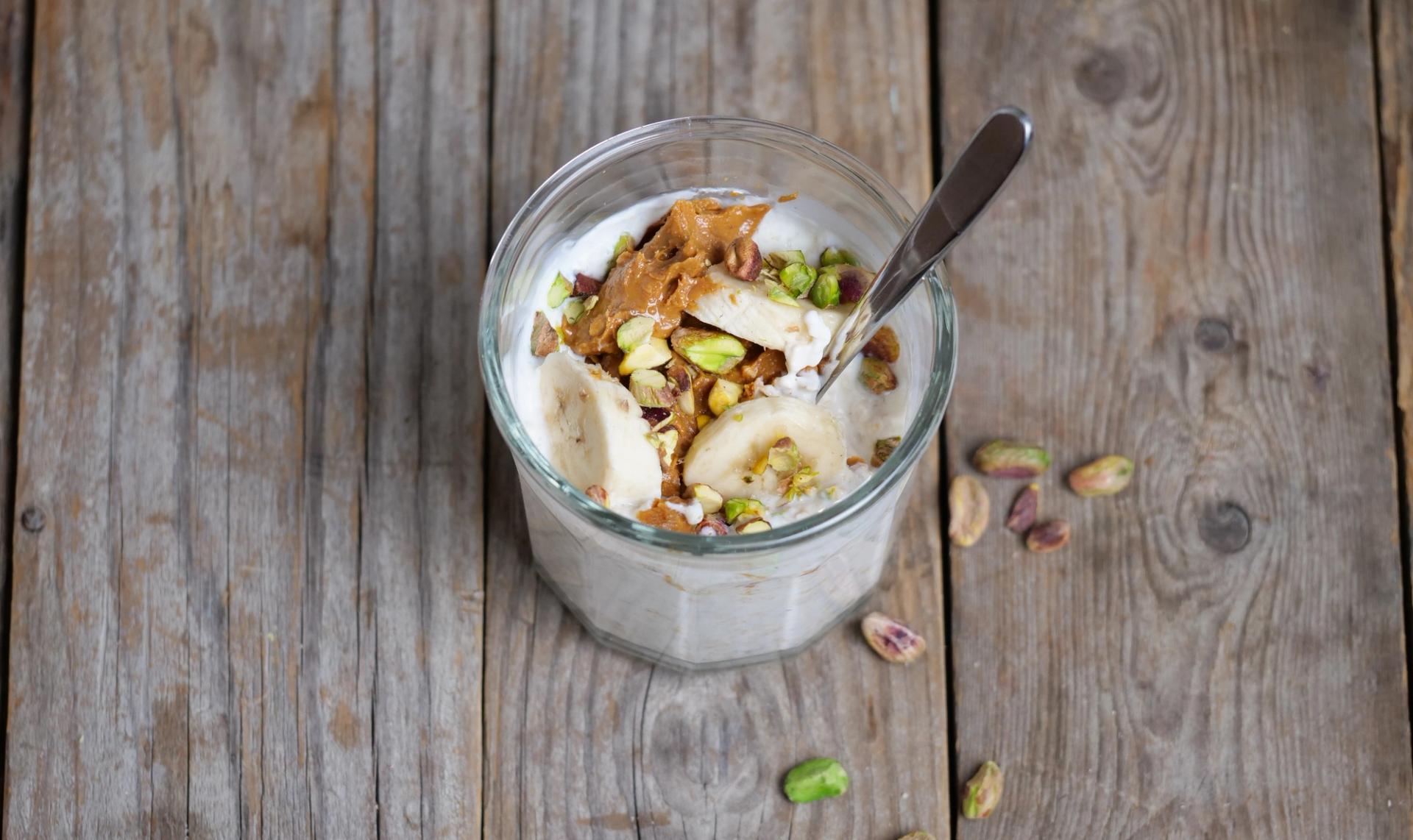 Et glass med kjøleskapsgrøt toppet med nøtter og peanøttsmør.