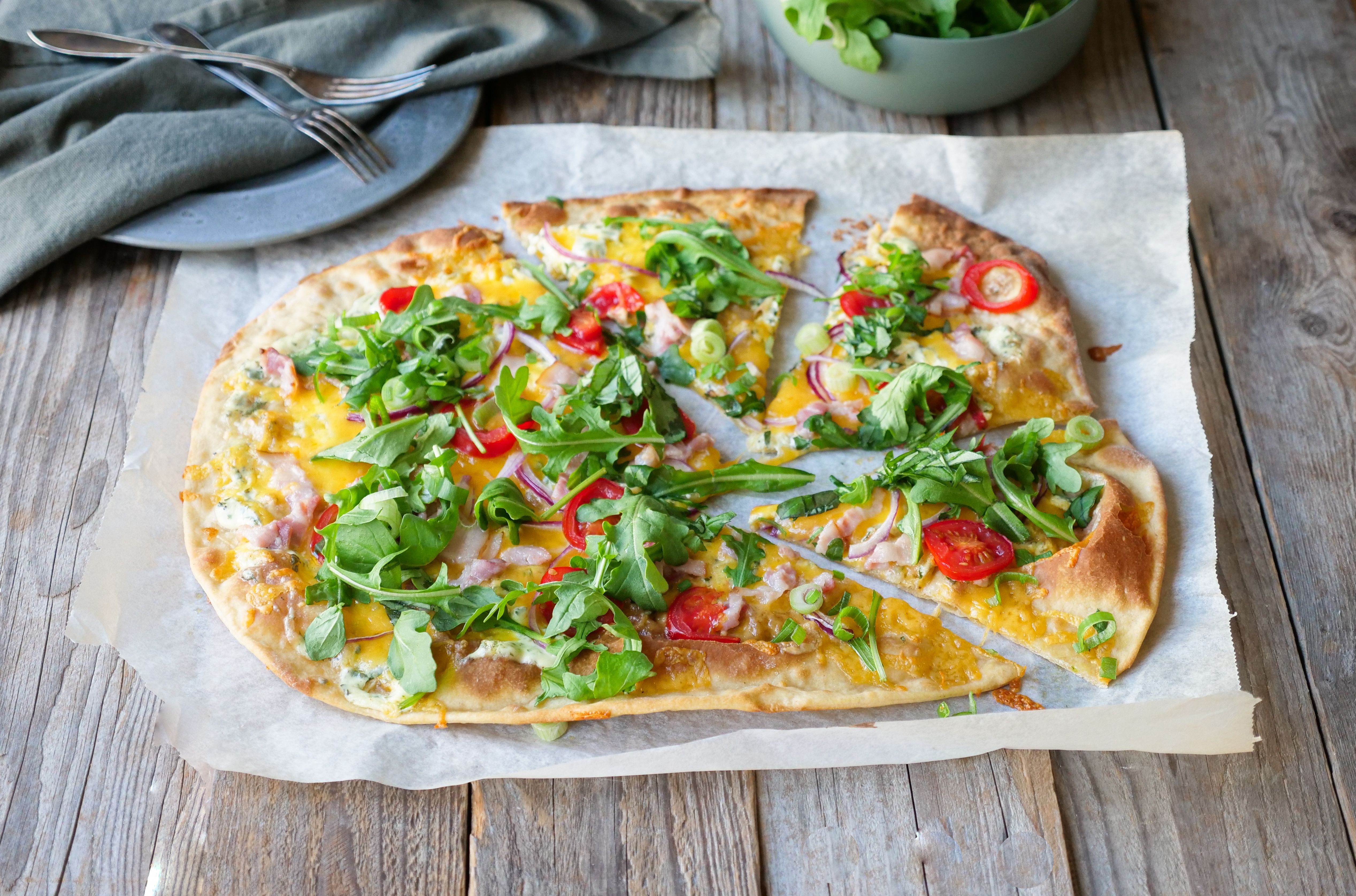 pizzapai toppet med ruccola liggende på et bord 
