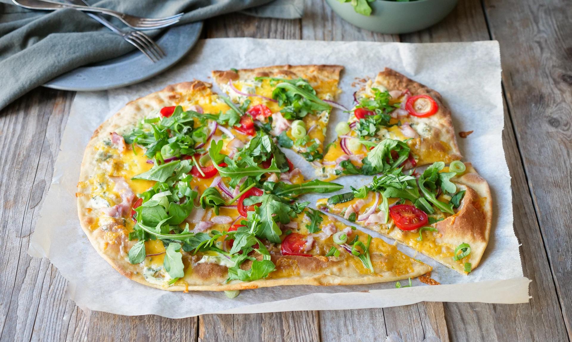 pizzapai toppet med ruccola liggende på et bord