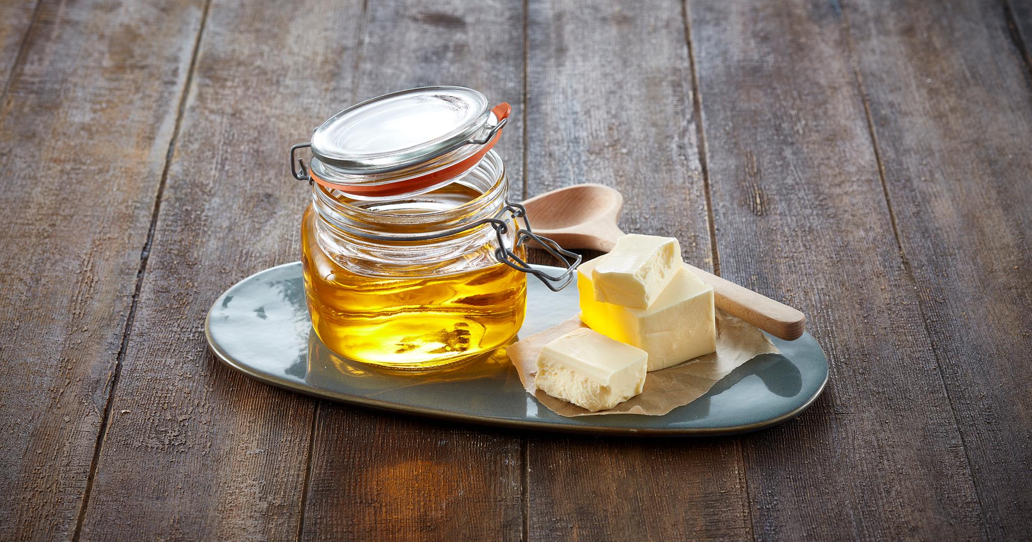 Klaret smør i en krukke, med skiver av smør ved siden av