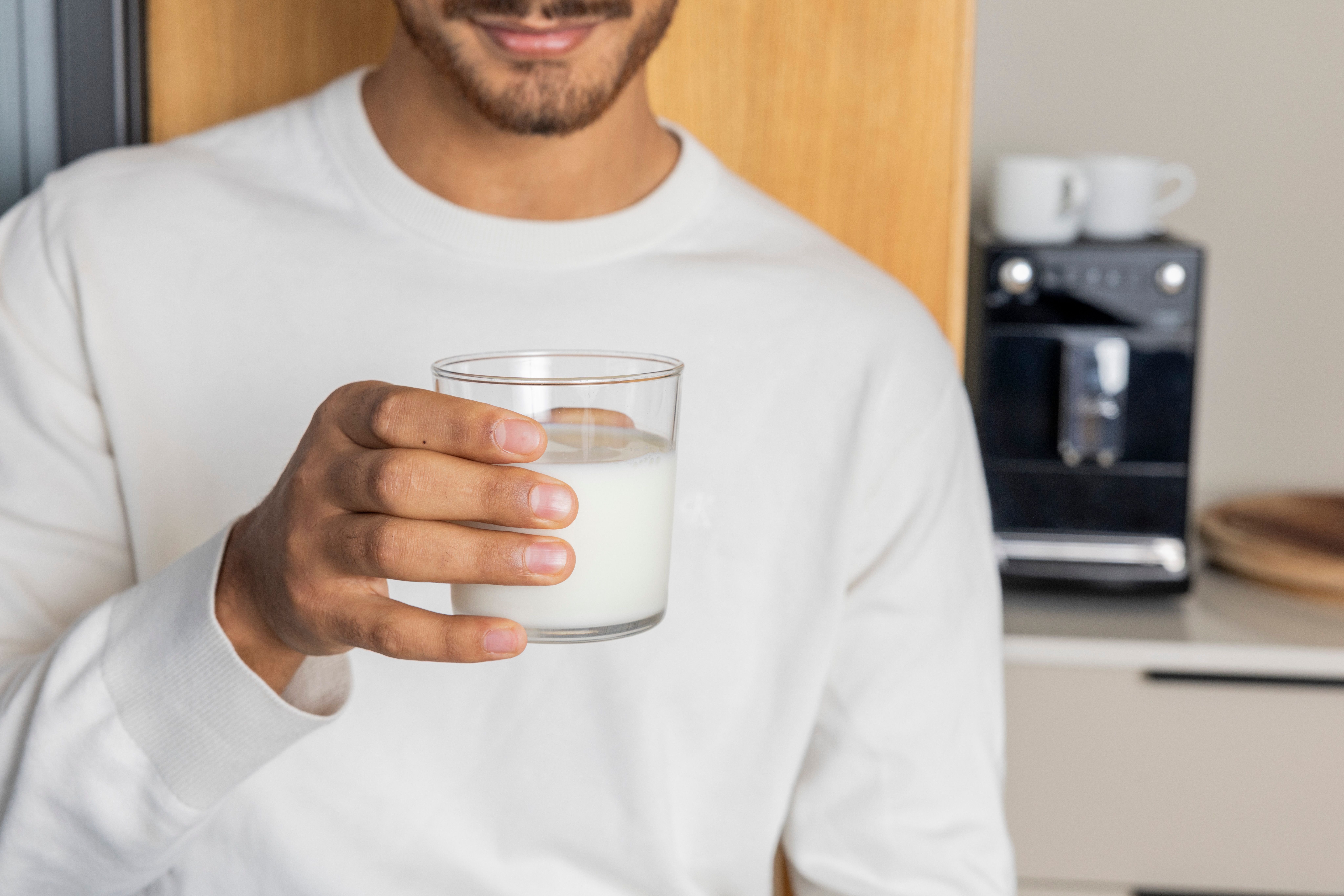 A hand holding a glass of milk.