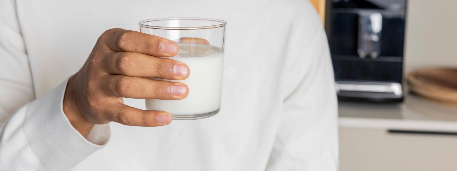 A hand holding a glass of milk.