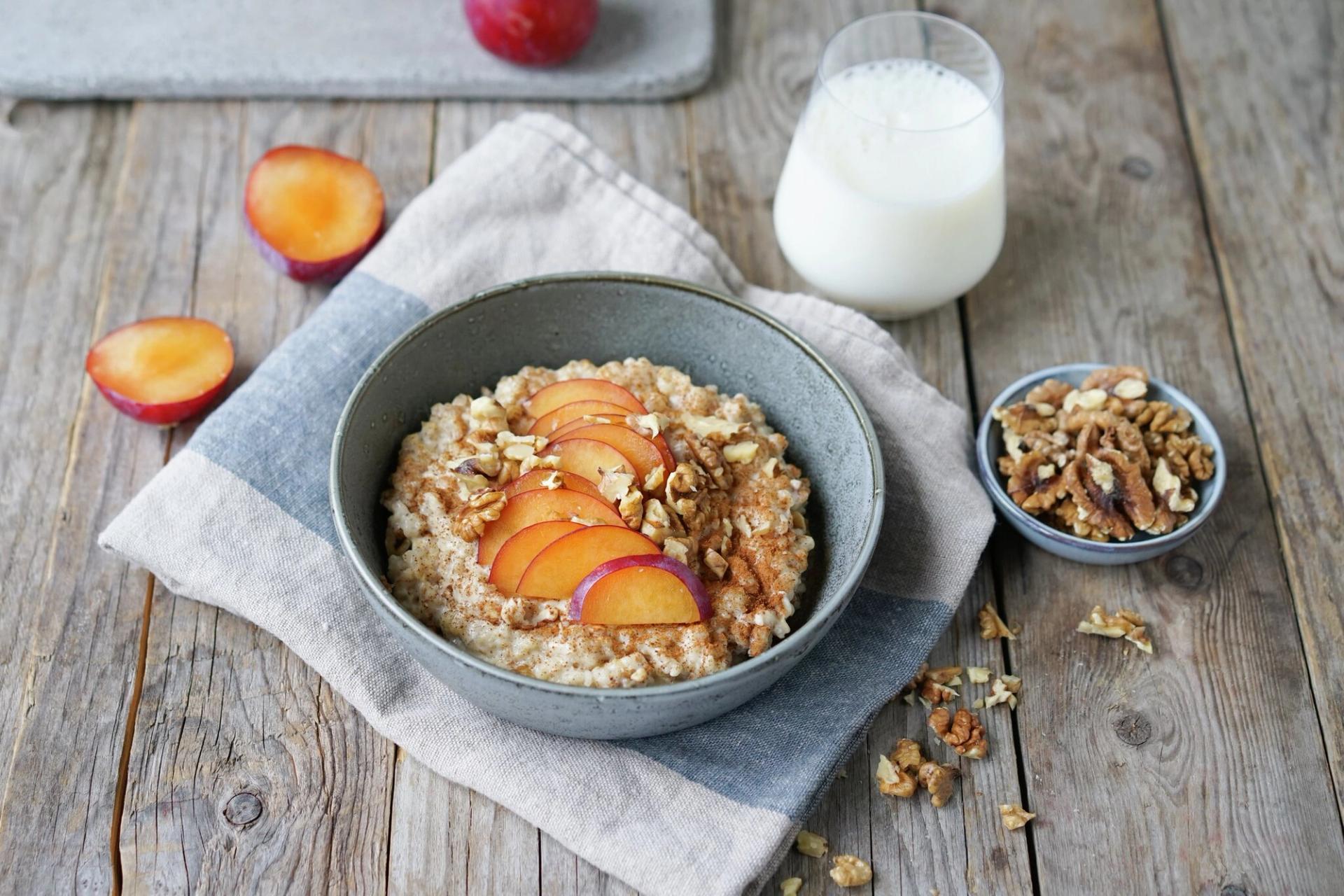 Havregrøt med nektarin, kanel, nøtter og et glass melk ved siden av