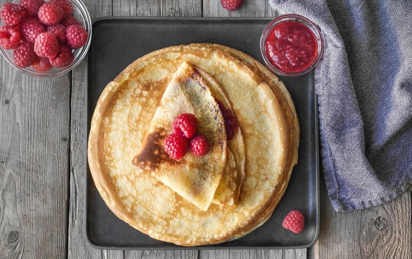 pannekaker toppet med bringebær og et glass melk
