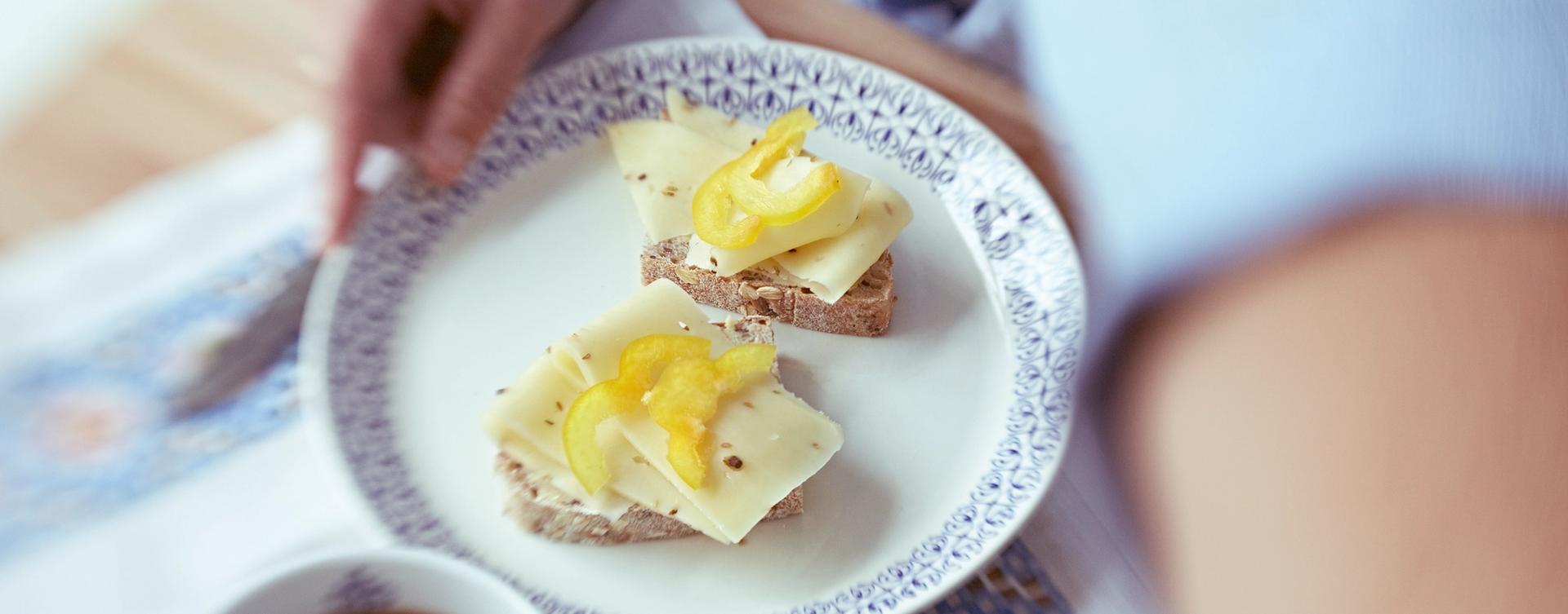 To brødskived med gulost og gul paprika på en tallerken.