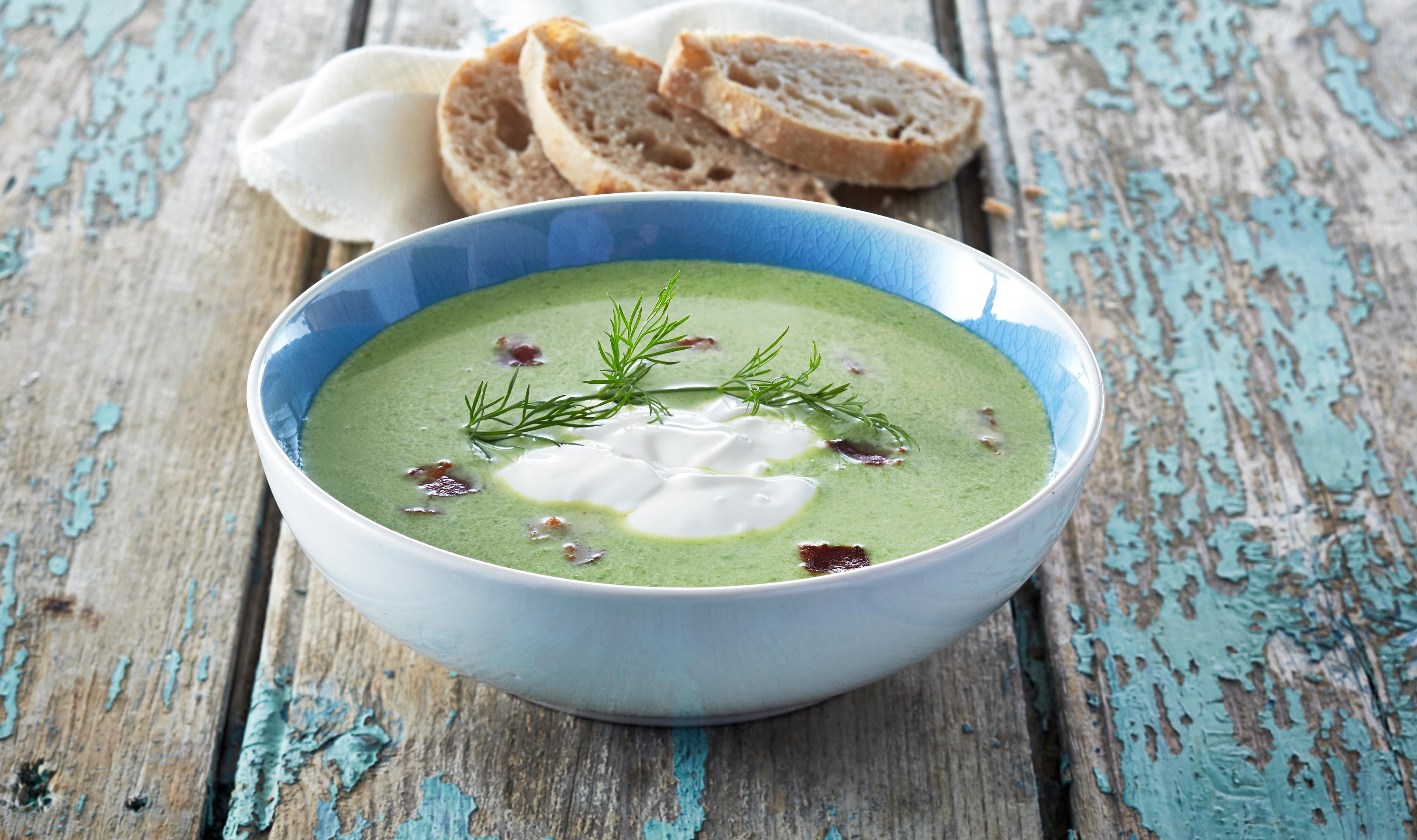 En porsjon ertesuppe toppet med kvarg med brød ved siden av.