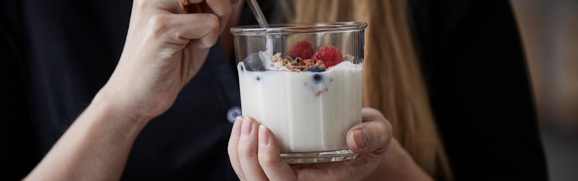 Kvinne spiser yoghurt med bær