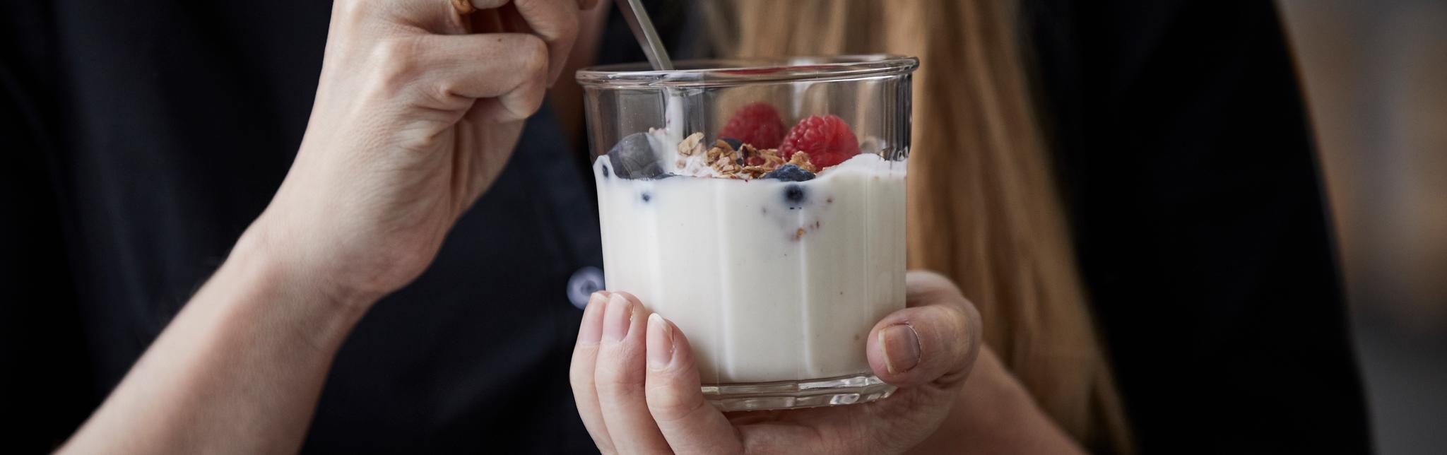 Kvinne spiser yoghurt med bær