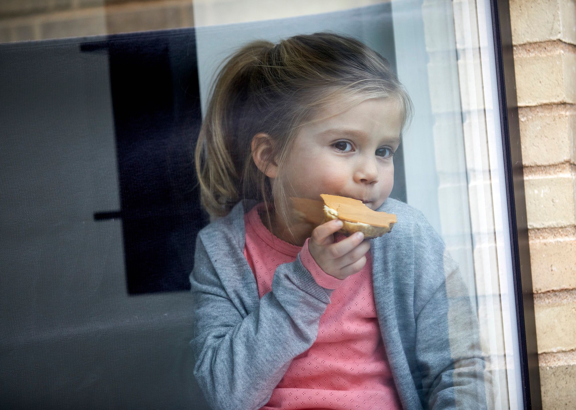 Jente spiser brødskive med brunost
