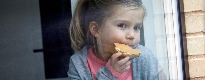 Jente spiser brødskive med brunost