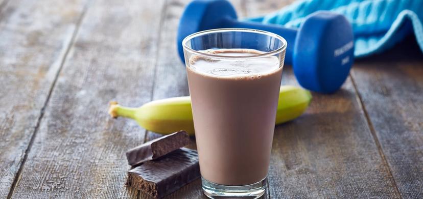 Et glass sjokolademelk, en proteinbar, en banan, et treningshåndkle og en manual.