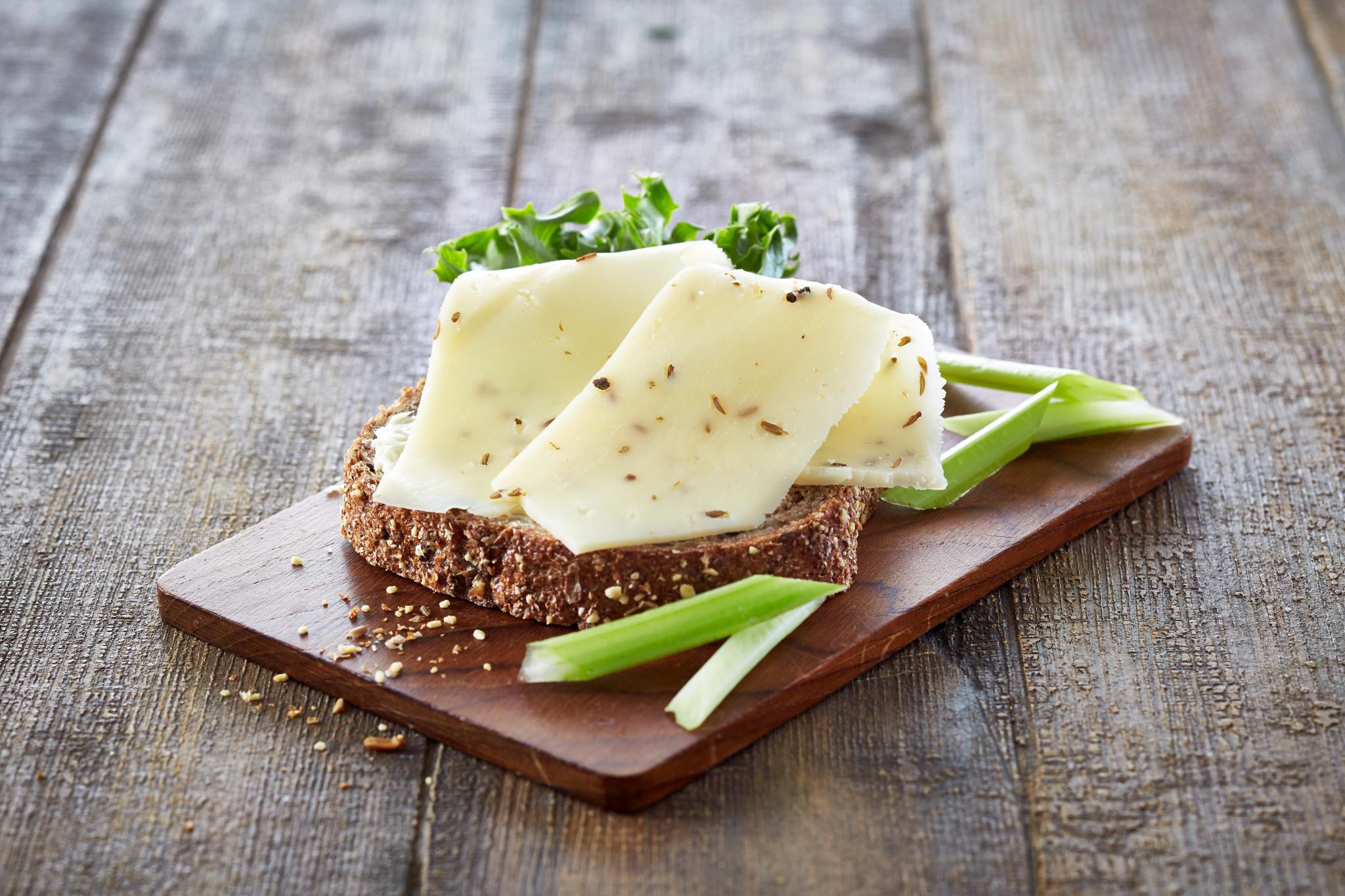 En grov brødskive med nøkkelost og salat, og litt stangselleri, på en trefjøl.