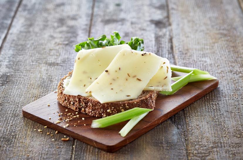 En grov brødskive med nøkkelost og salat, og litt stangselleri, på en trefjøl.