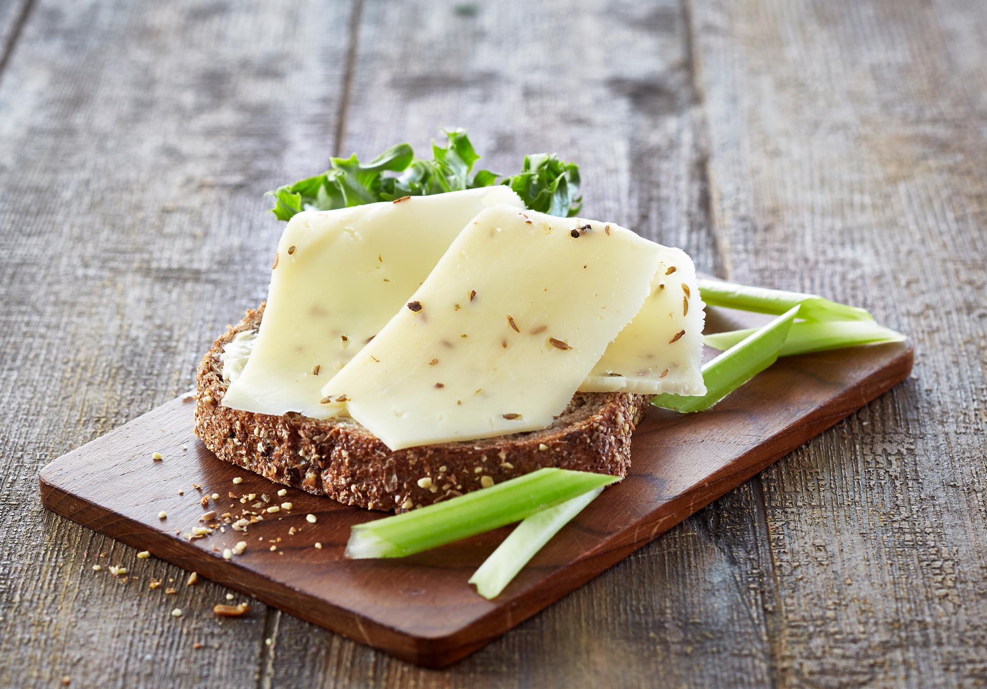 En grov brødskive med nøkkelost og salat, og litt stangselleri, på en trefjøl.