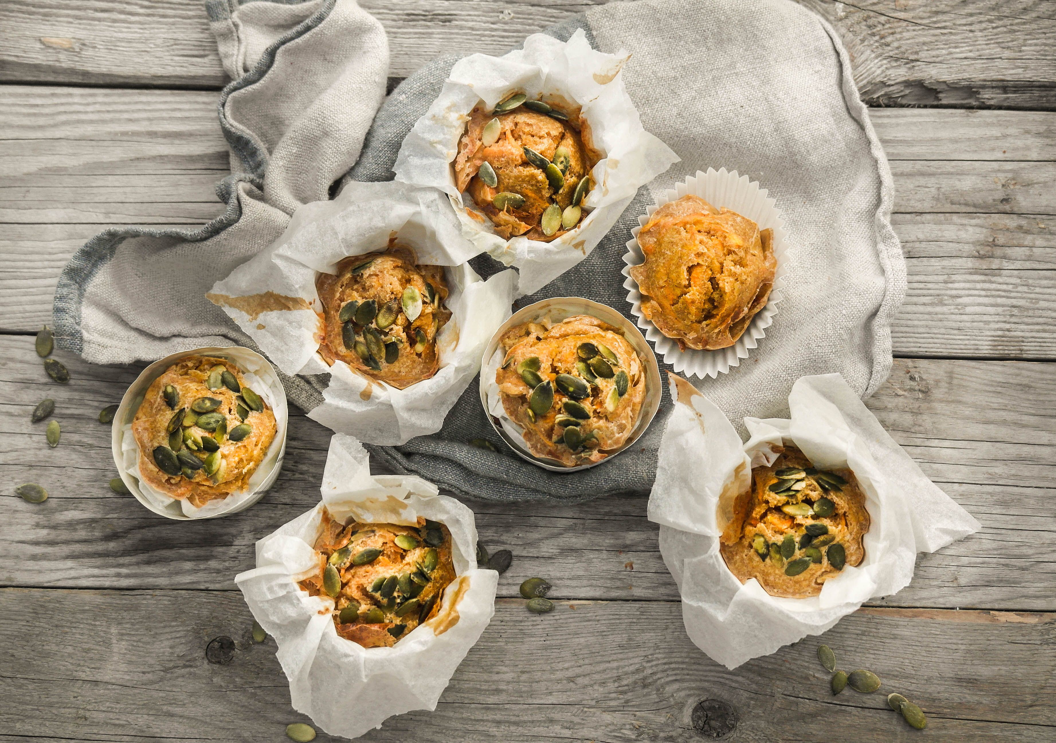 Flere gulrotmuffinser toppet med gresskarkjerner