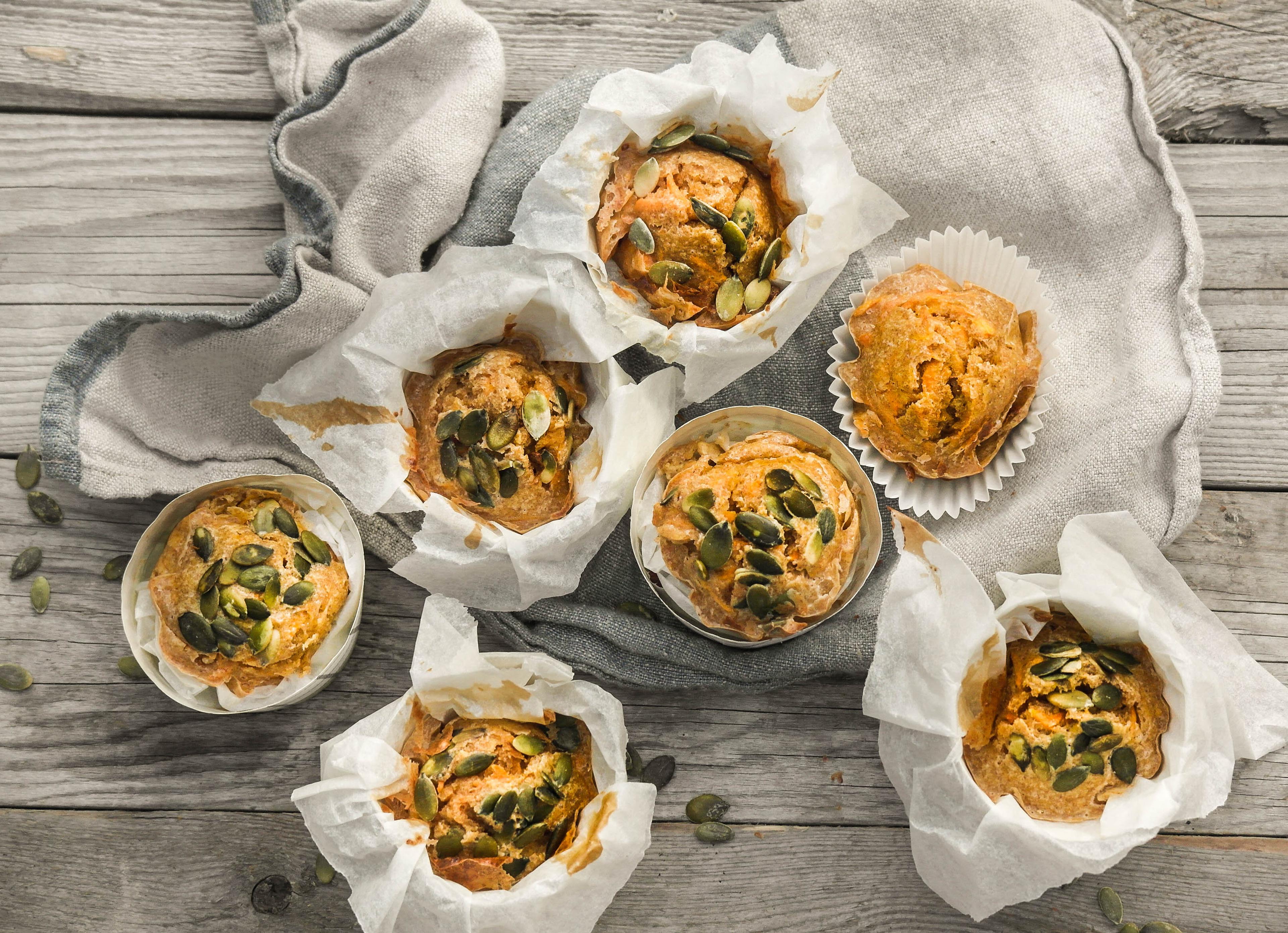 Flere gulrotmuffinser toppet med gresskarkjerner