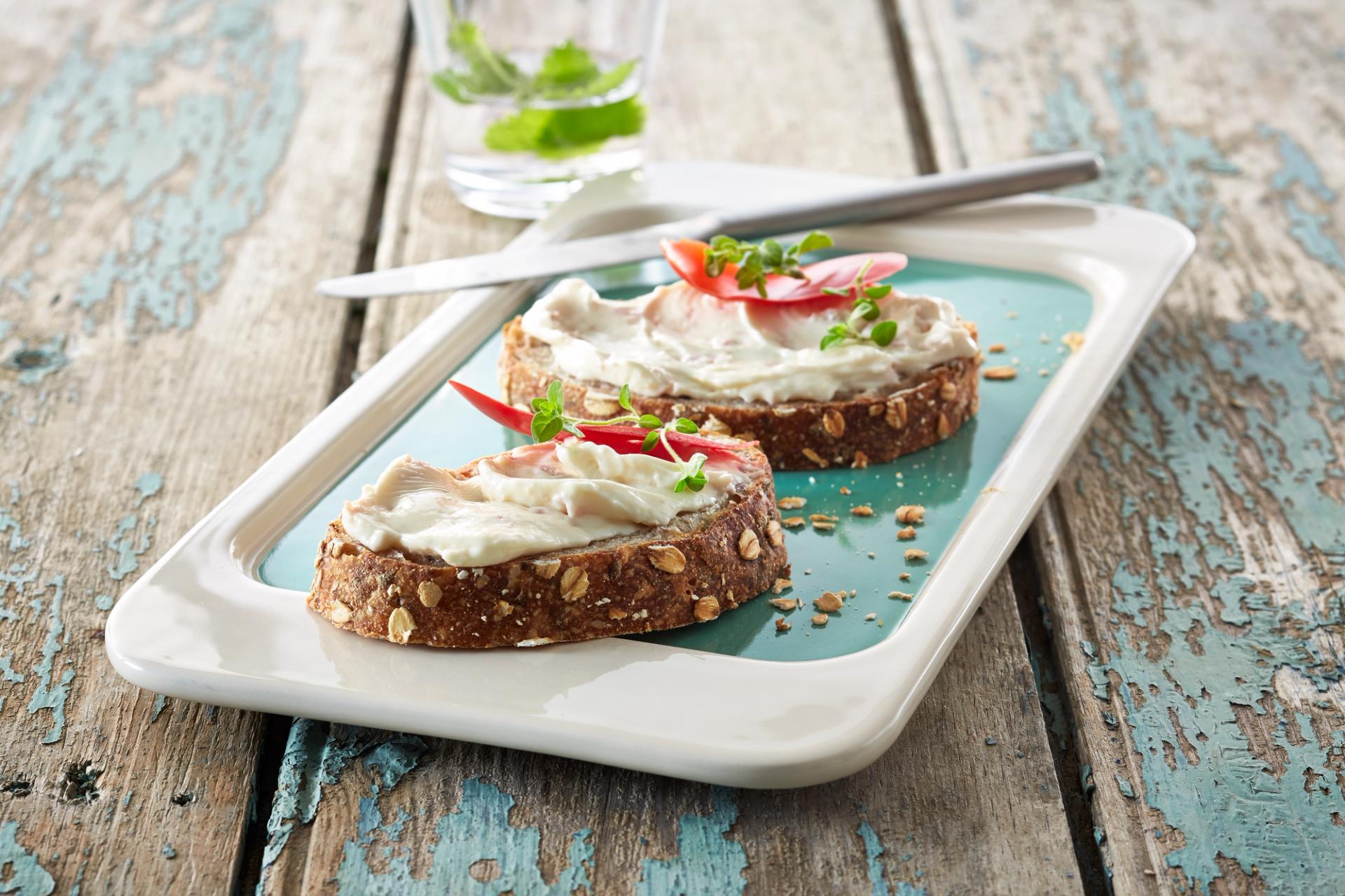 To brødskiver med smøreost og paprika på en tallerken.