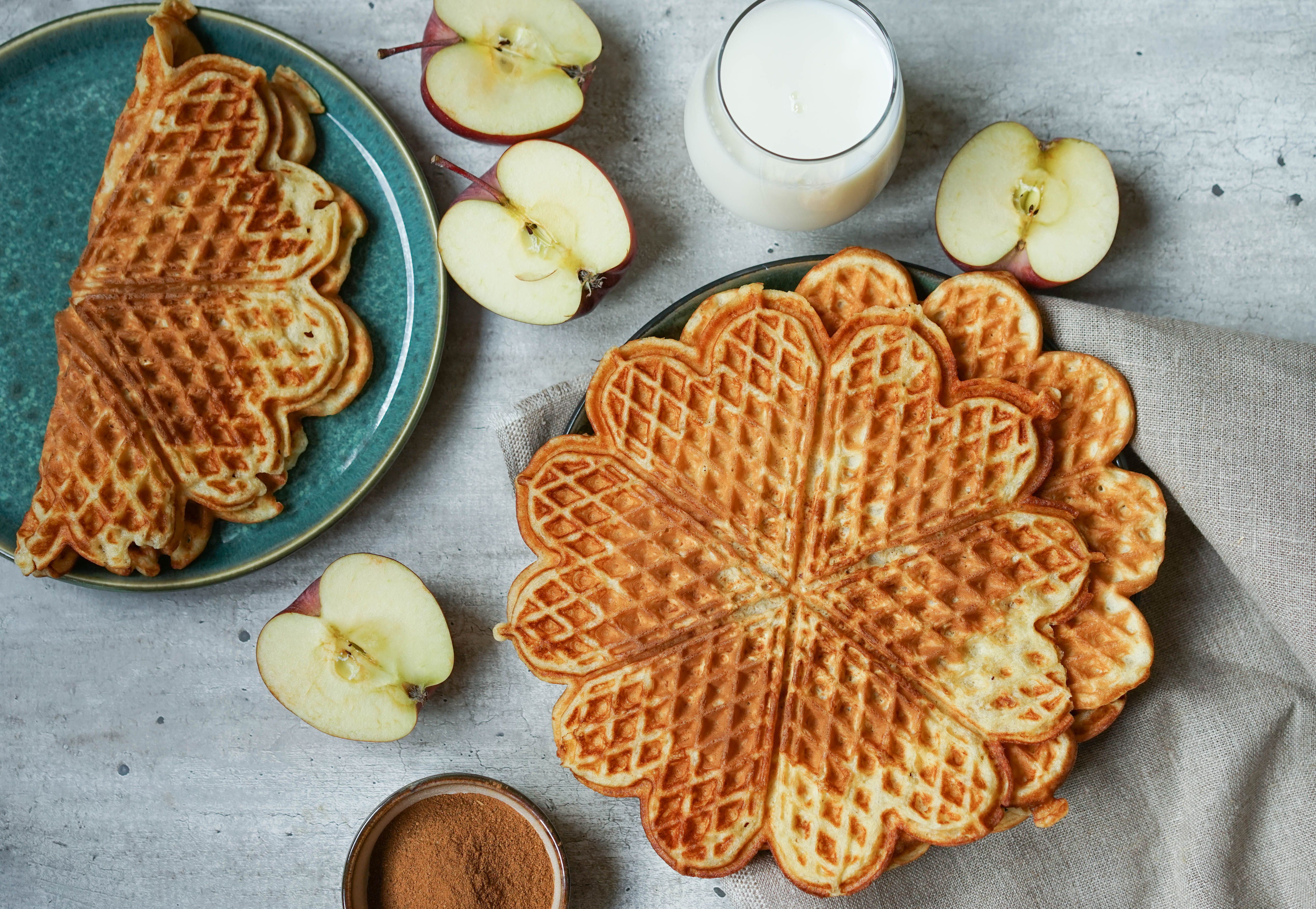 eplevafler med kanel i stabel med epler delt i to ved siden og et glass melk