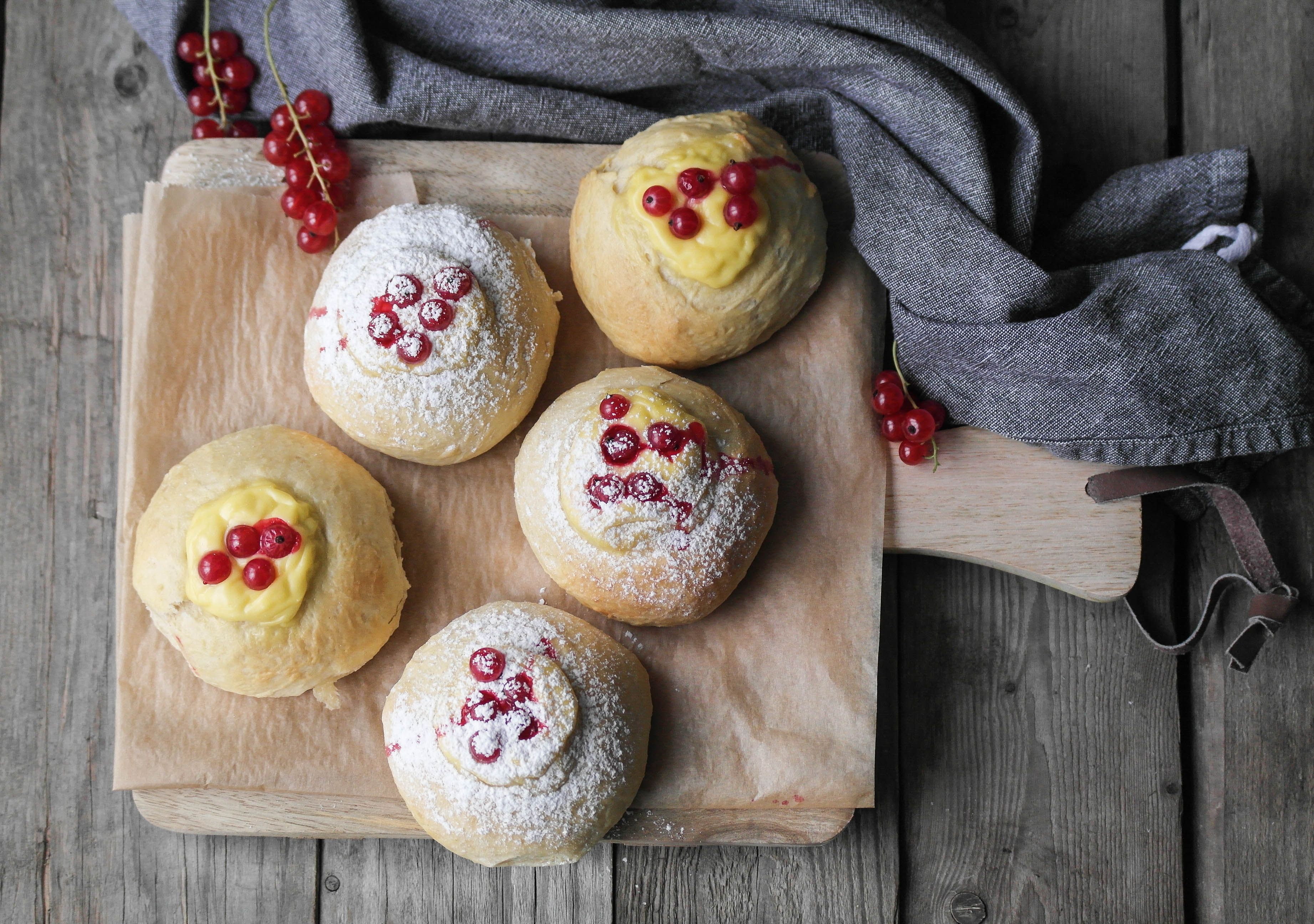 Fem nybakte skoleboller med rips og vaniljekrem på en fjøl