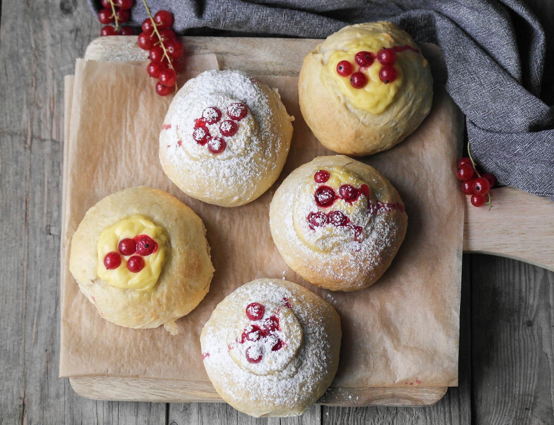 Fem nybakte skoleboller med rips og vaniljekrem på en fjøl