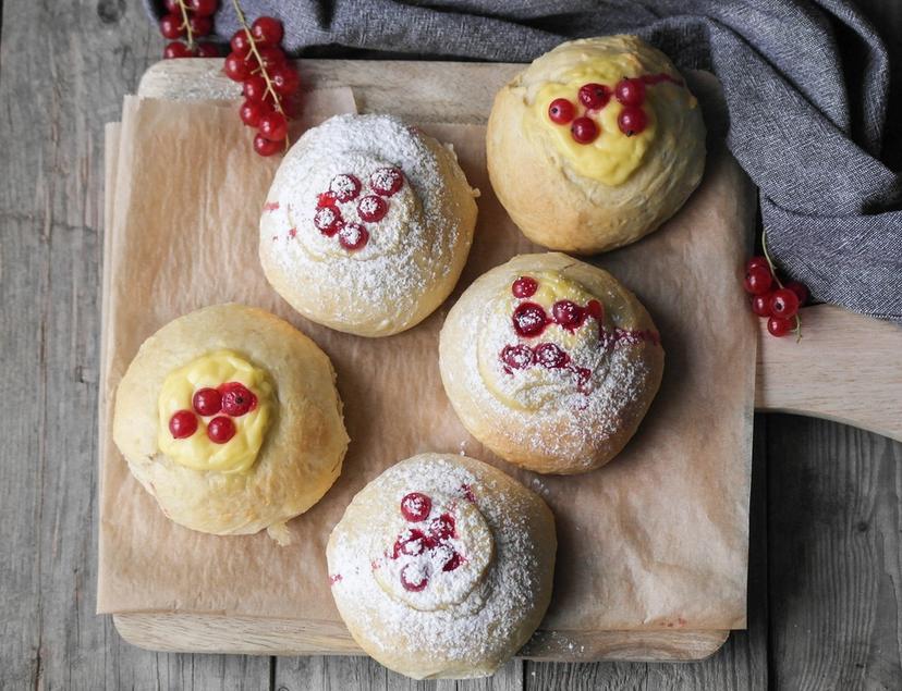 Fem nybakte skoleboller med rips og vaniljekrem på en fjøl