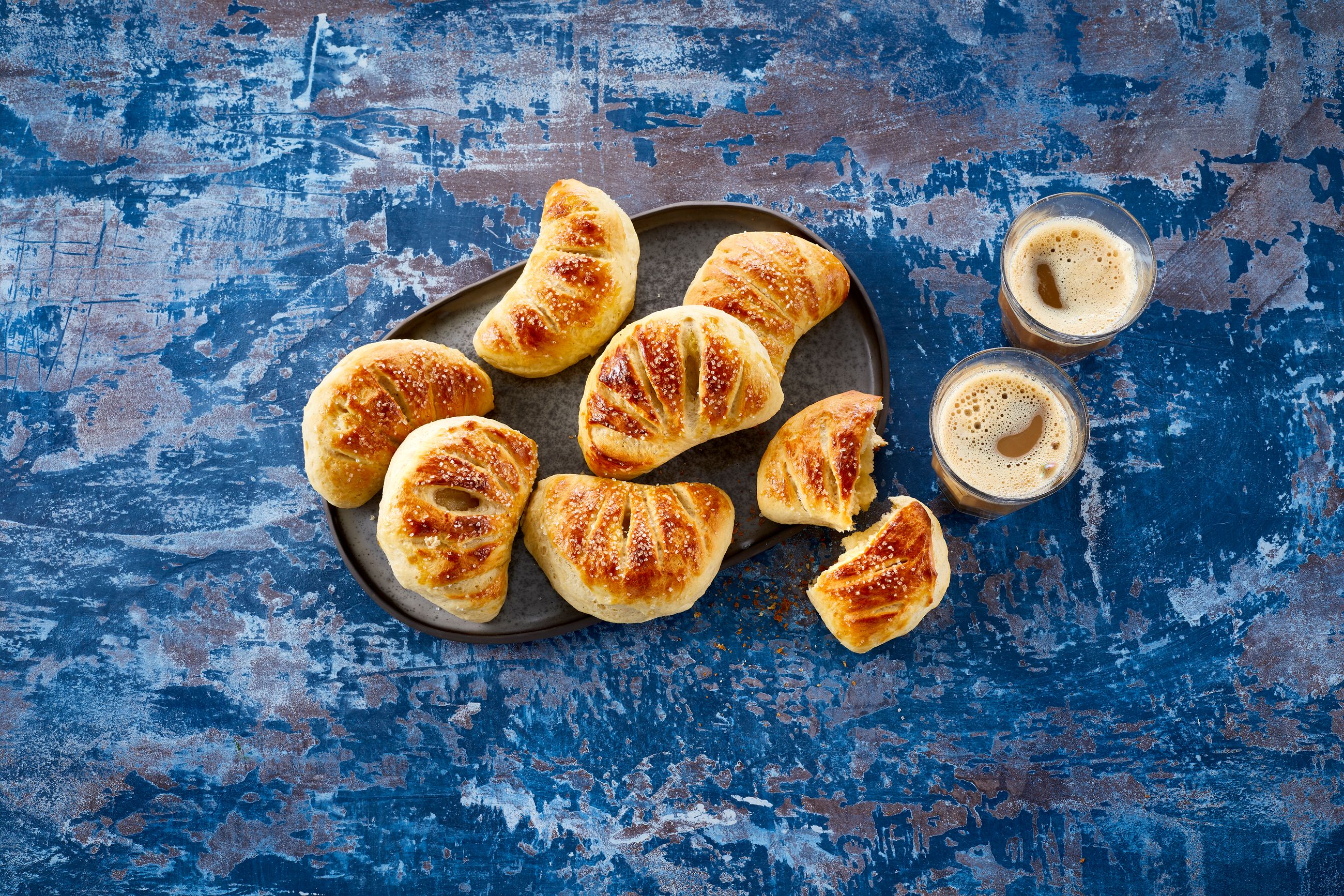 Vifter med mandelmasse på en tallerken med to glass kaffe ved siden