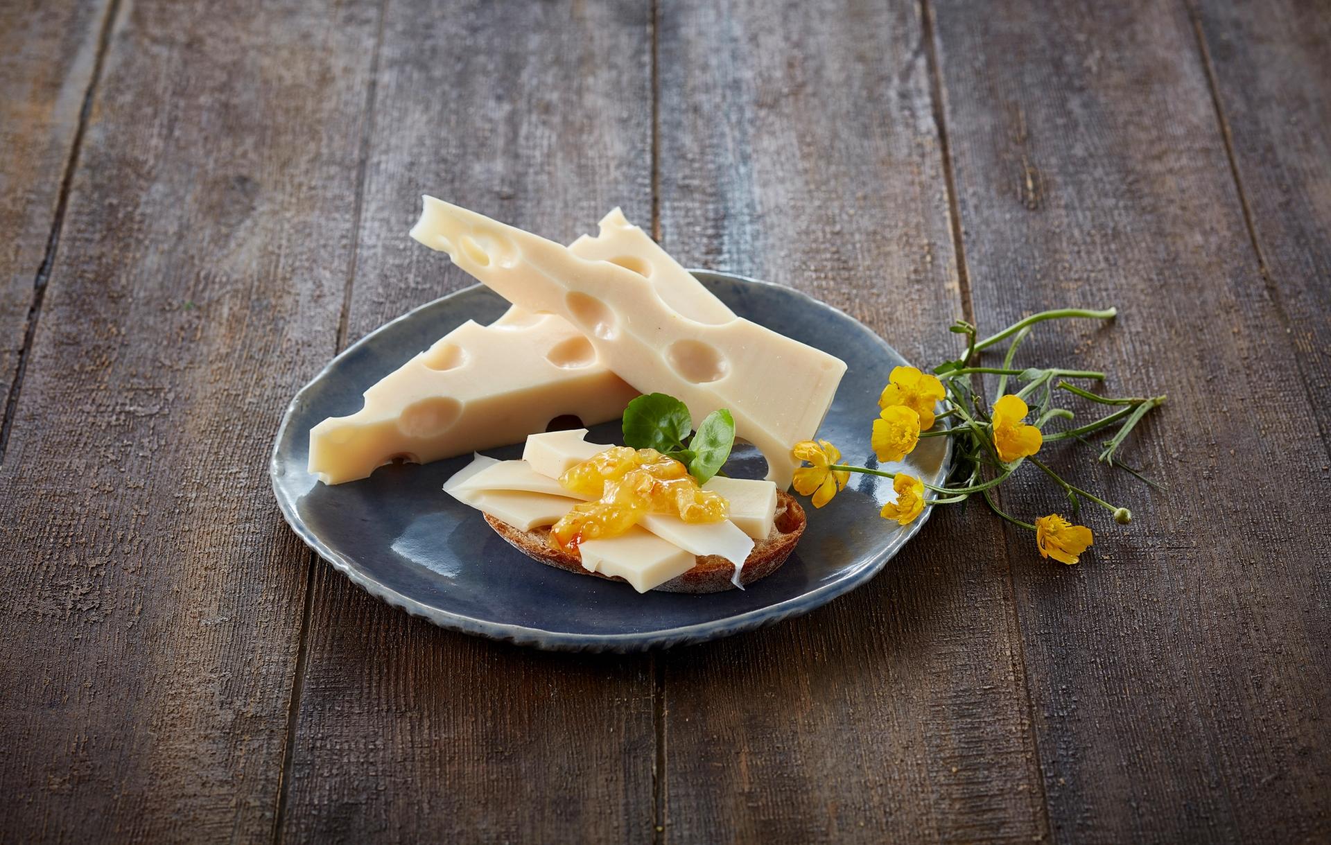 Oppskåret sveitserost på en blå tallerken, med noen gule blomster ved siden