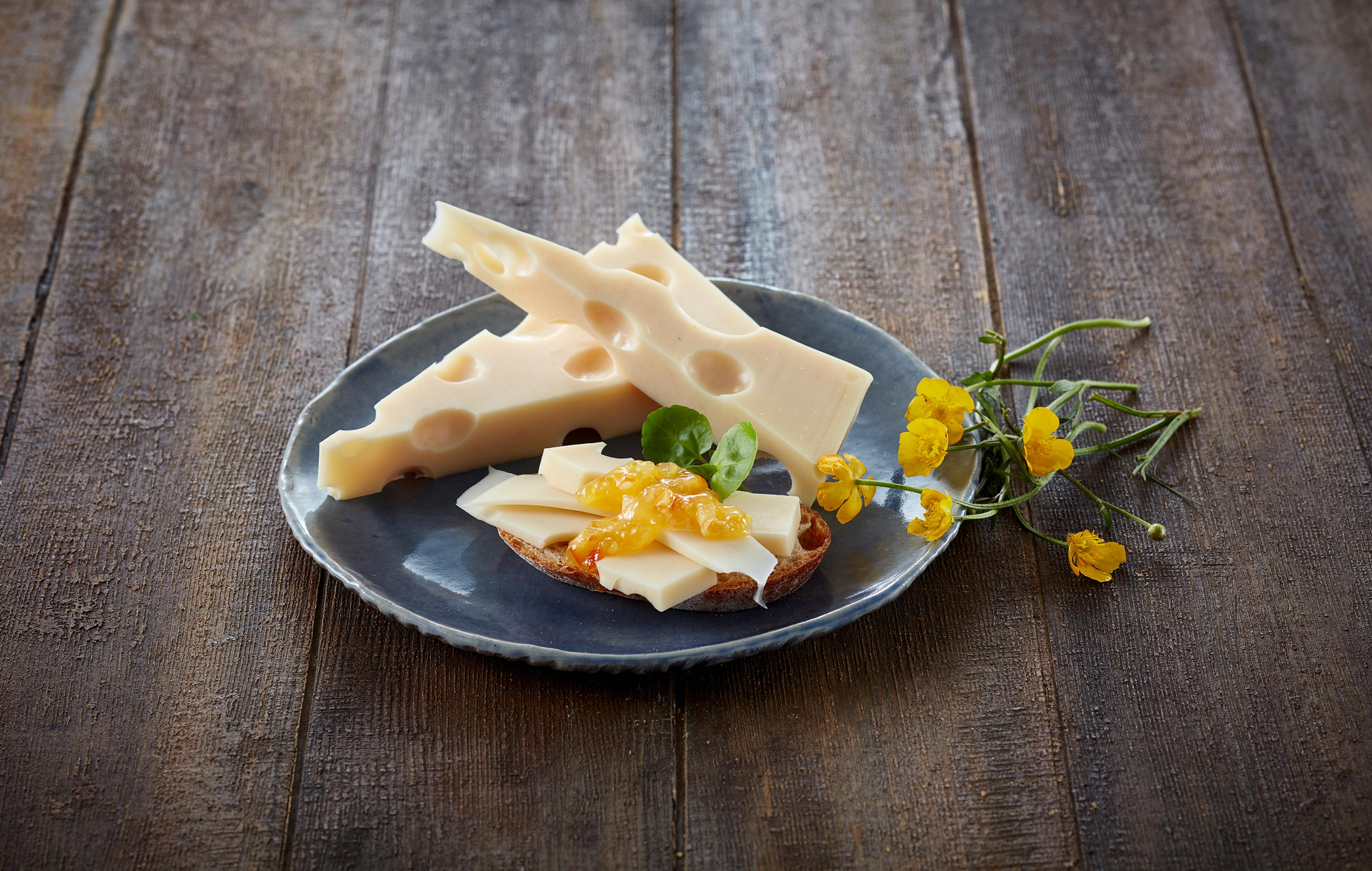 Oppskåret sveitserost på en blå tallerken, med noen gule blomster ved siden