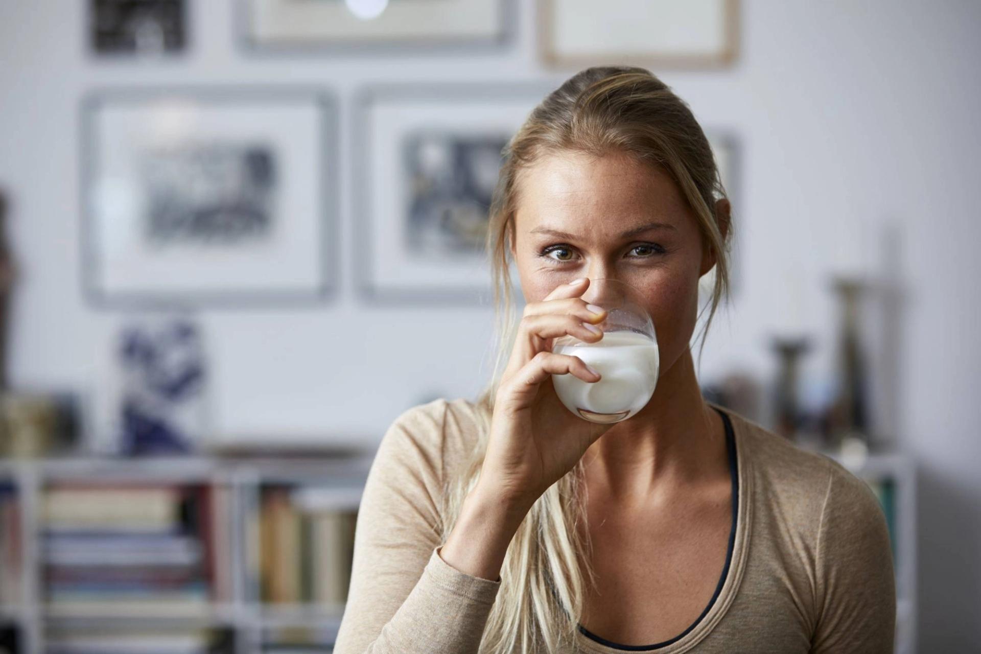 Kvinne drikker melk og ser inn i kameraet
