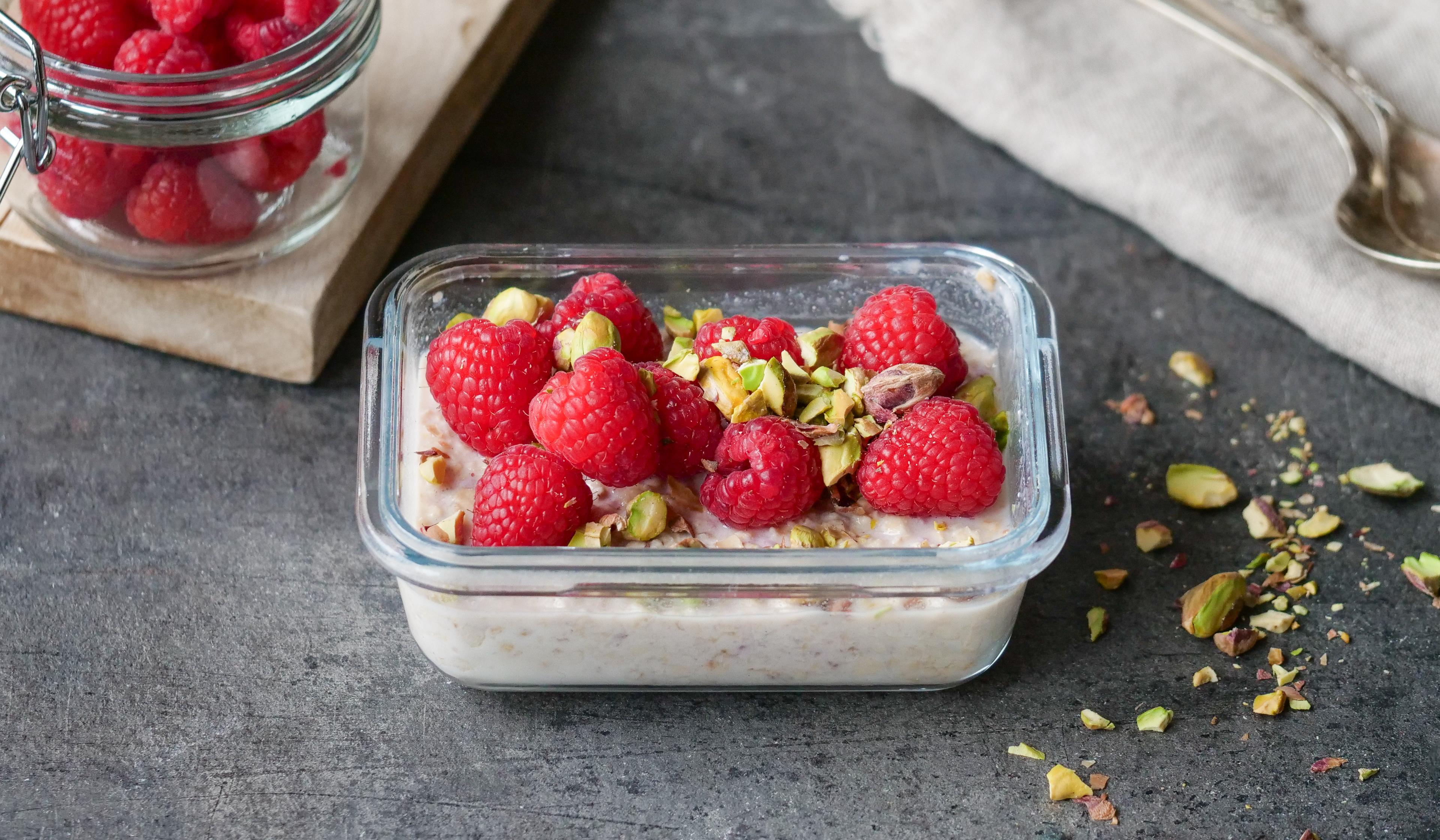Kjøleskapsgrøt toppet med bringebær og hakkede pistasjnøtter