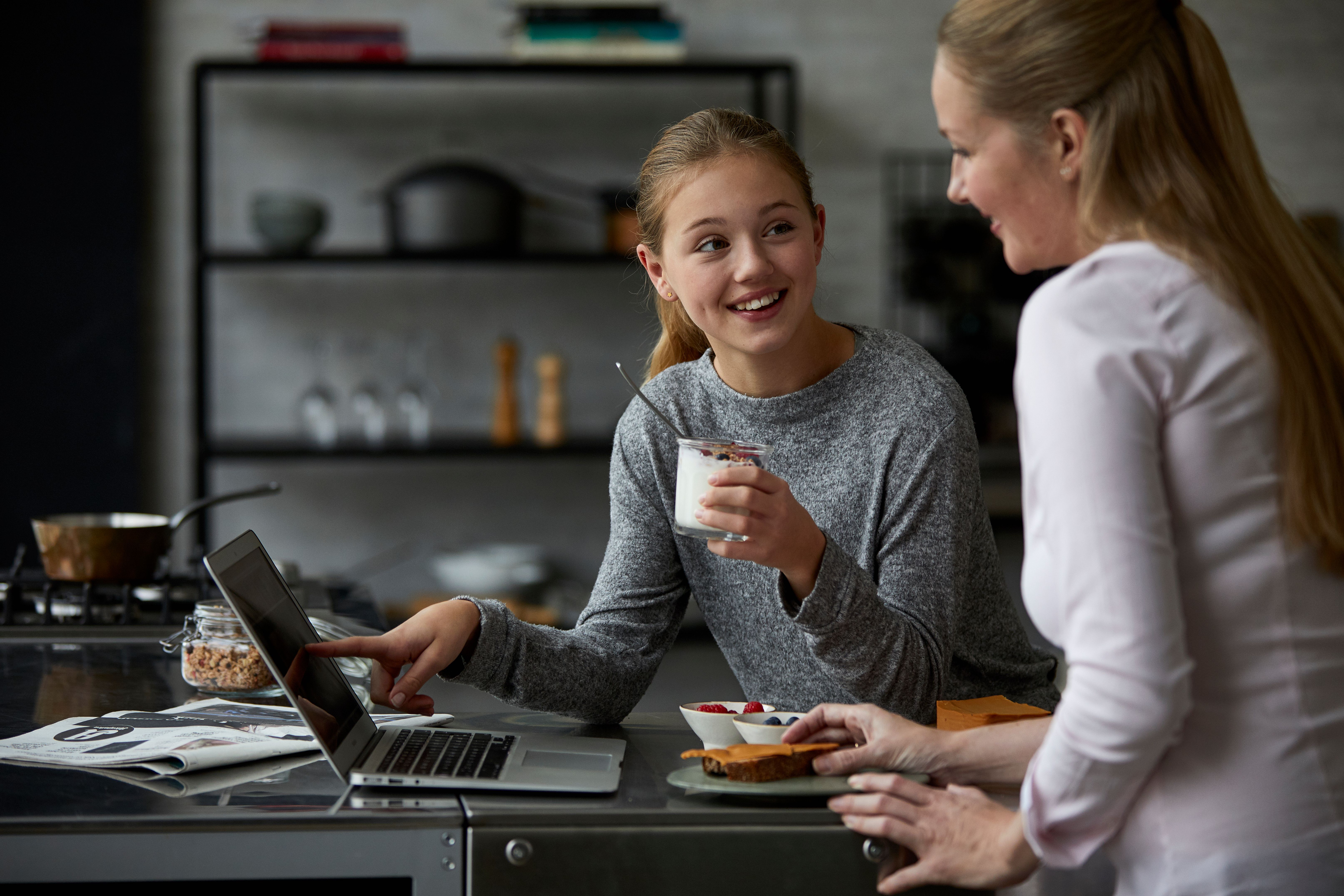 Jente spiser yoghurt med mor