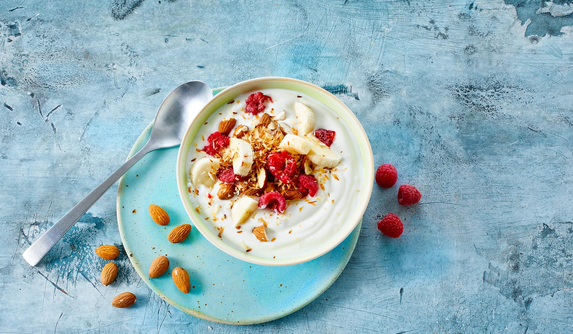 skål med yoghurt naturell, toppet med bringebær og hakkede mandler