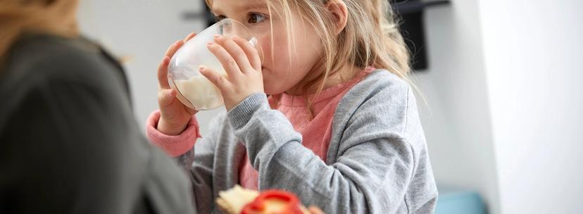 Mor med brødskive og ostepålegg og barn med melkeglass
