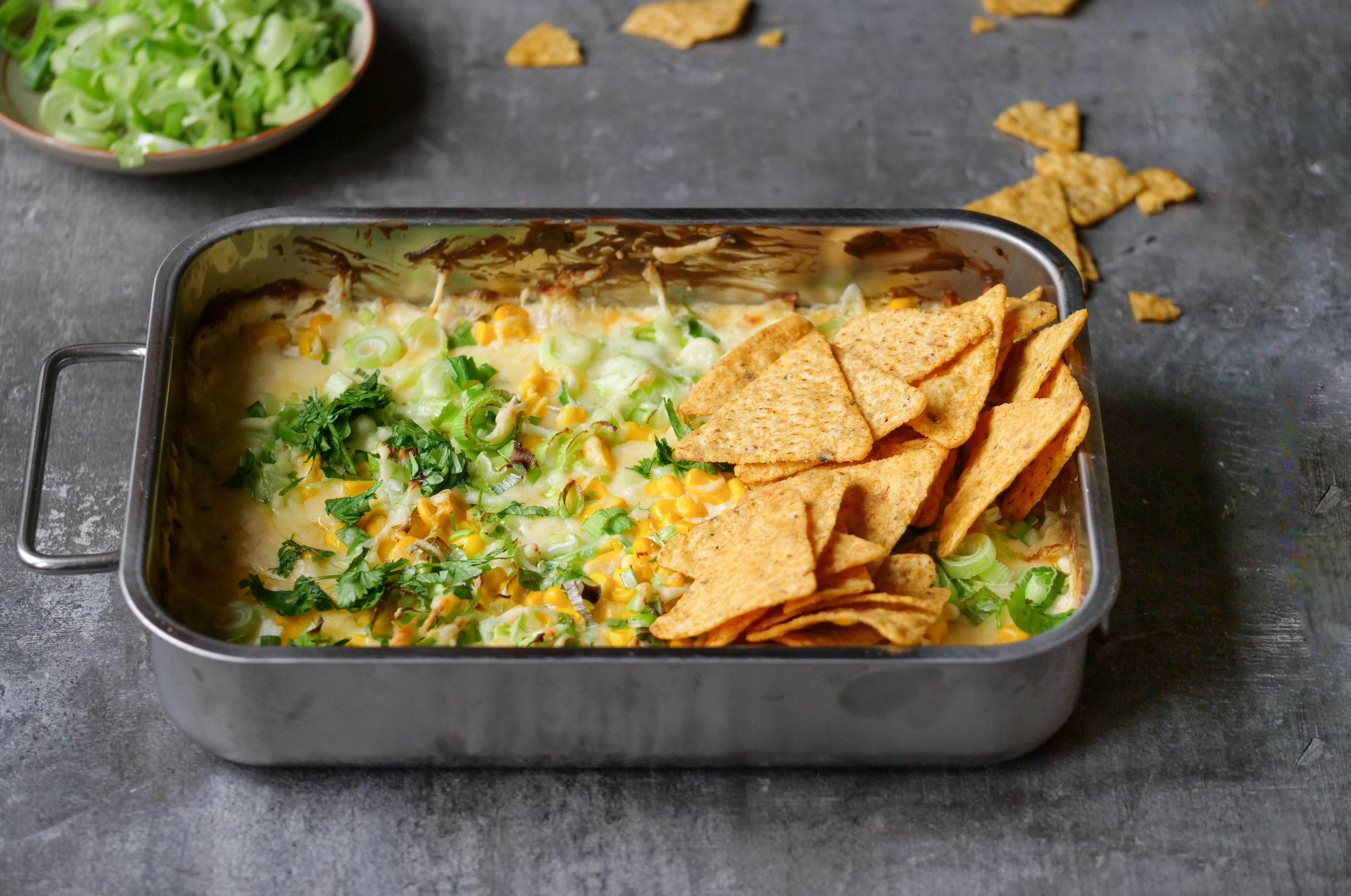 En form med ostedipp toppet med urter og tortillachips 