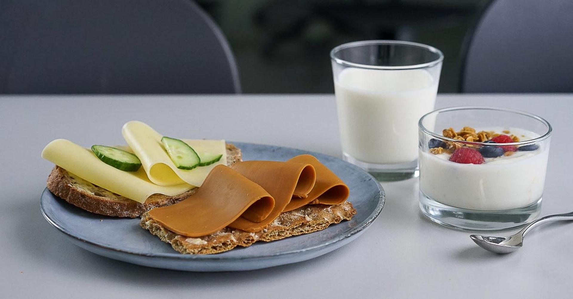 Tallerken med knekkebrød med ost, glass med melk, skål med yoghurt