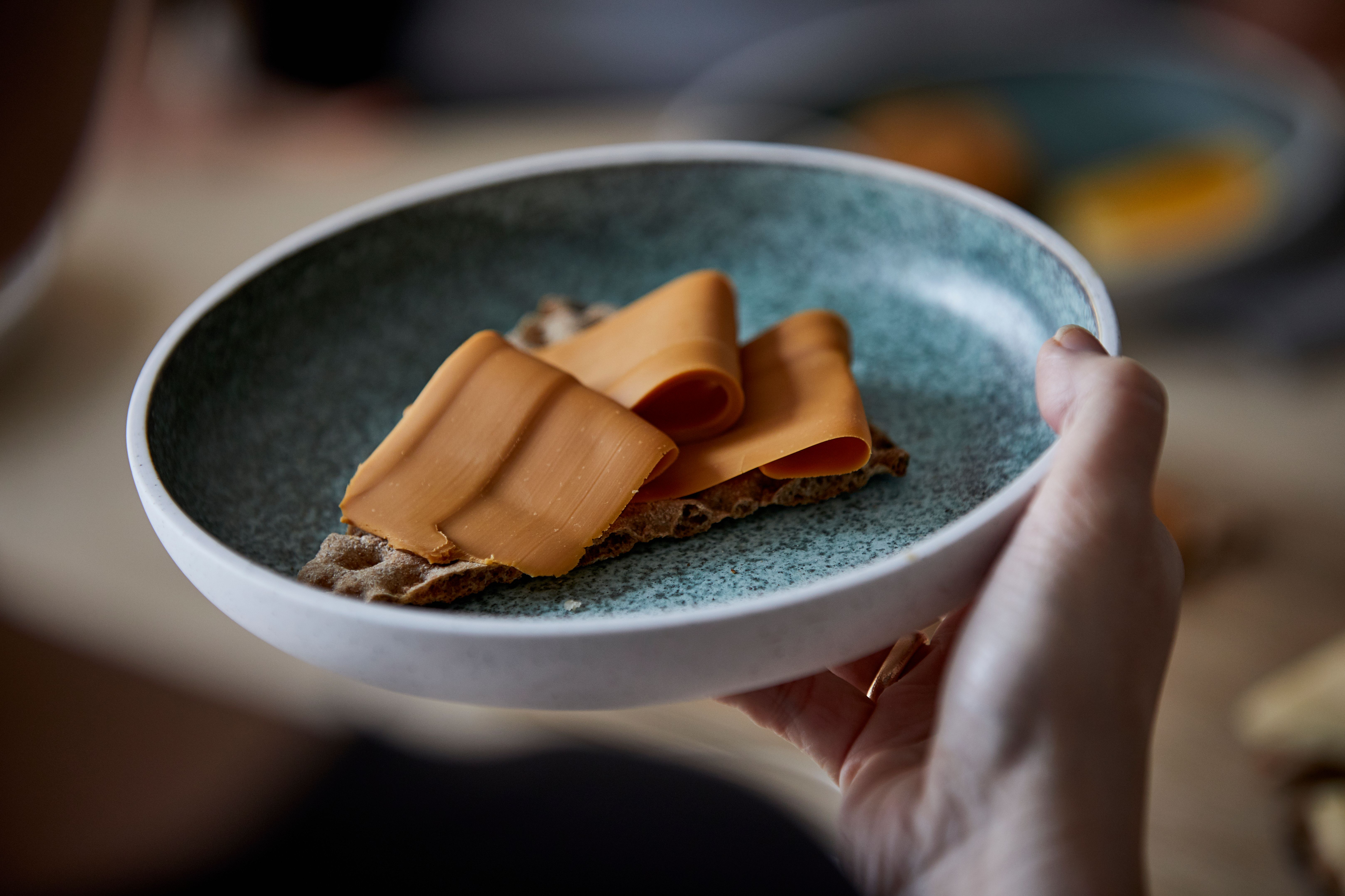 Grønn tallerken med et knekkebrød med brunost