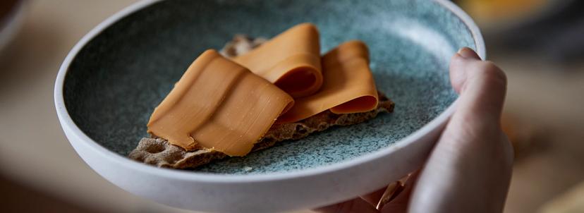 Grønn tallerken med et knekkebrød med brunost