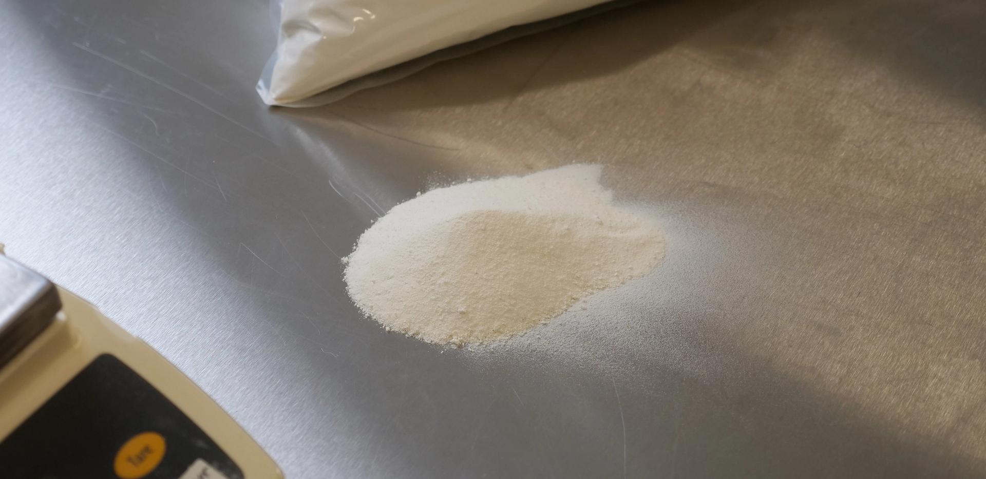 Melkepulver på metallbenk ved siden av vekt