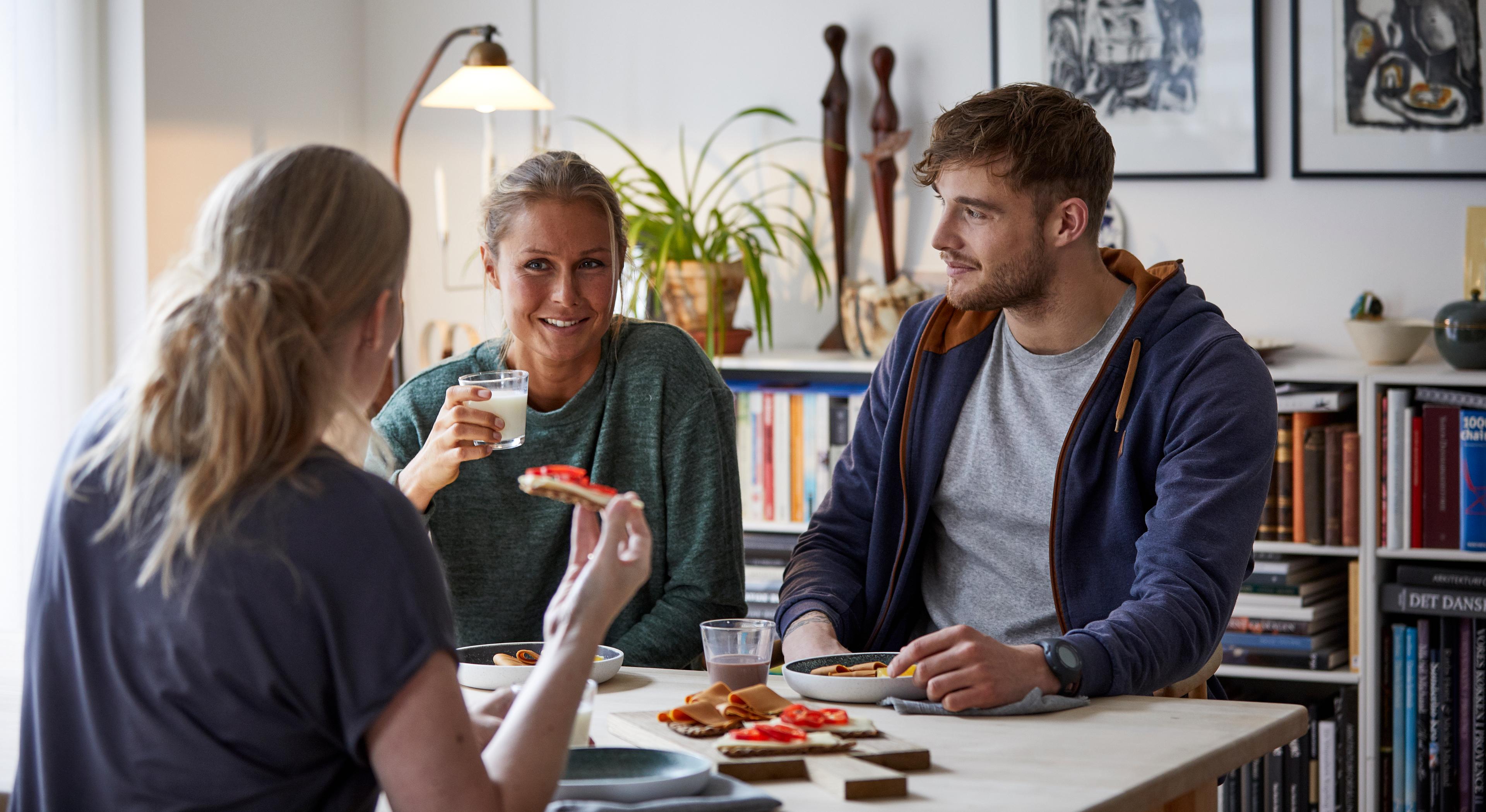 Tre unge voksne rundt et bord og spiser